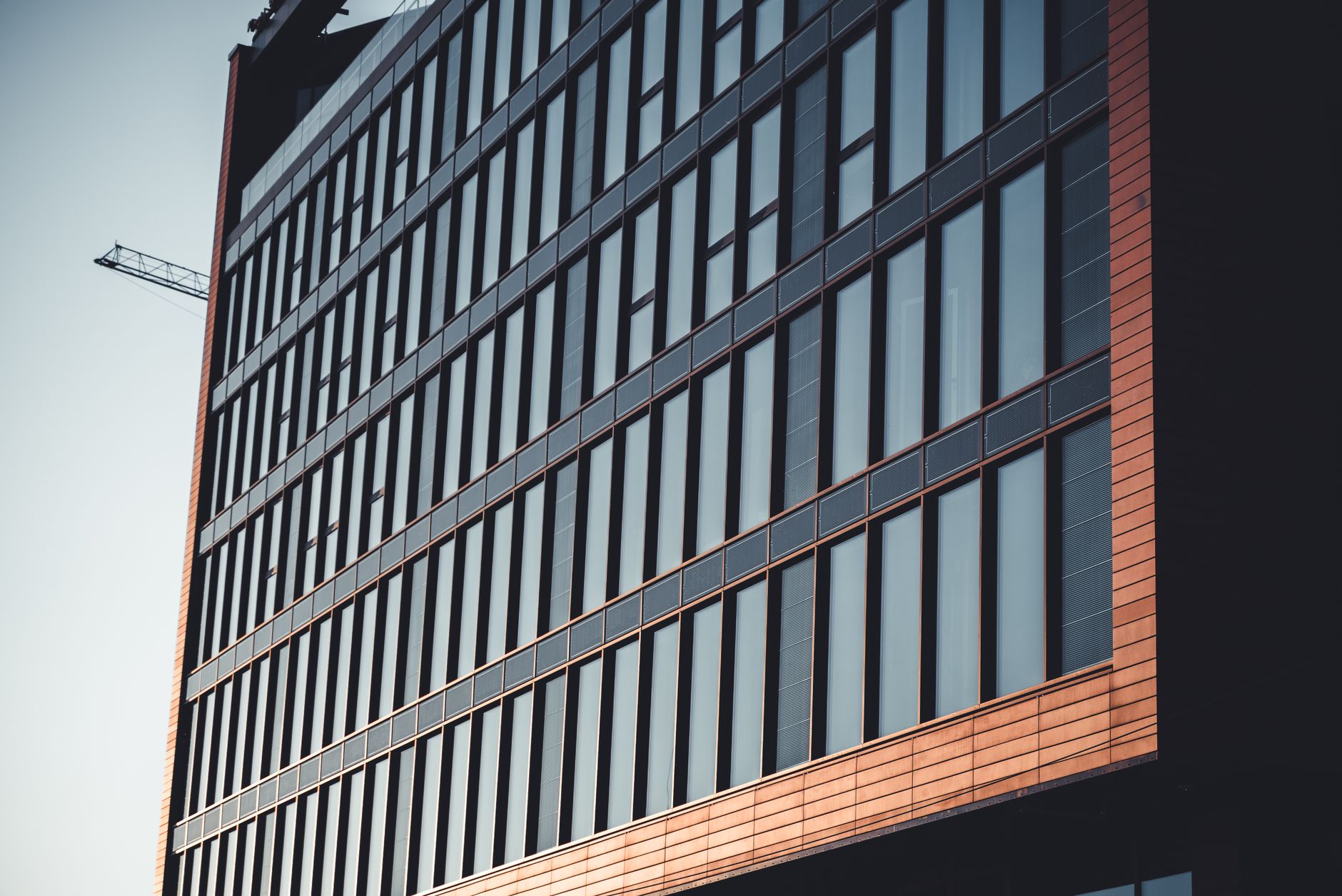 exterior of a modern tech campus office building at dusk with floor-to-ceiling glass windows reflecting city lights
