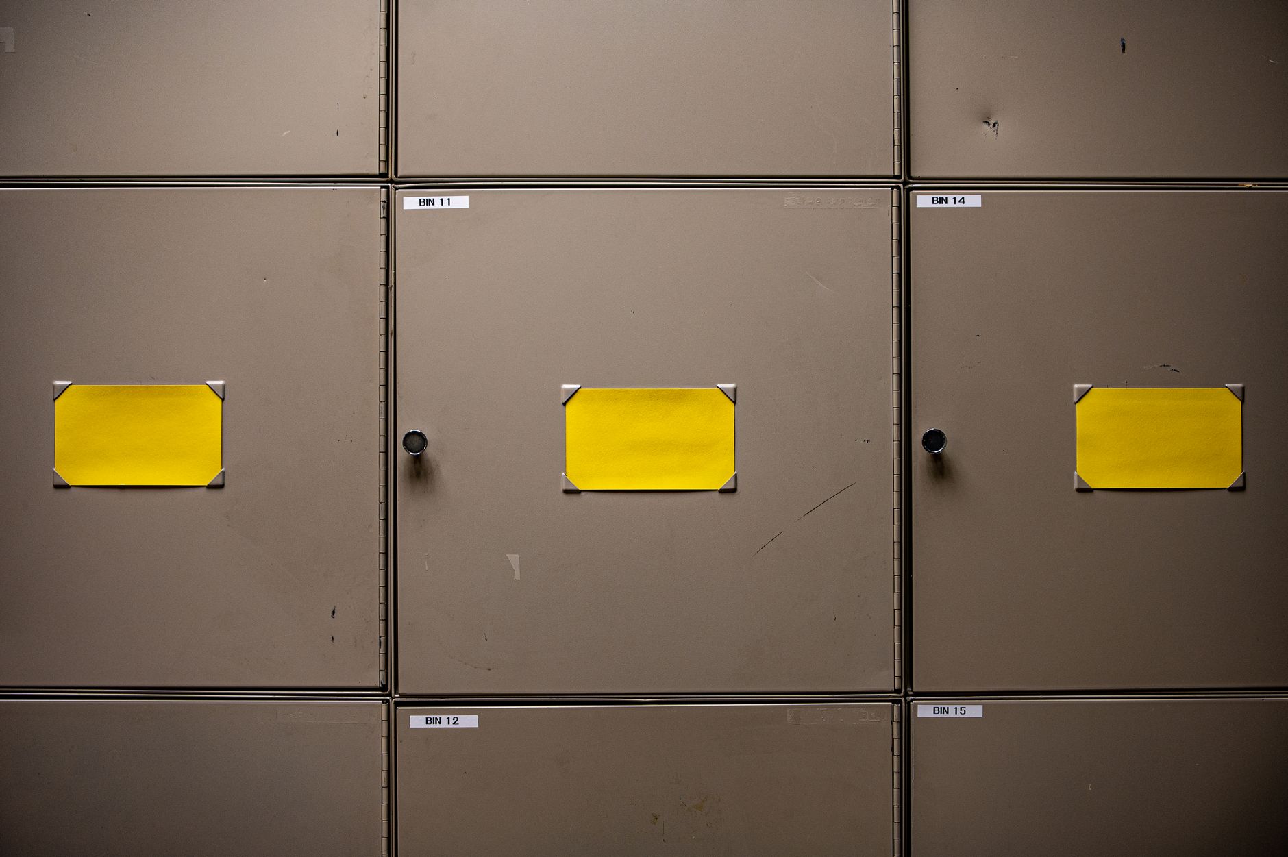 rows of document filing cabinets inside a formal government archive room, with overhead fluorescent lighting and labeled drawer fronts
