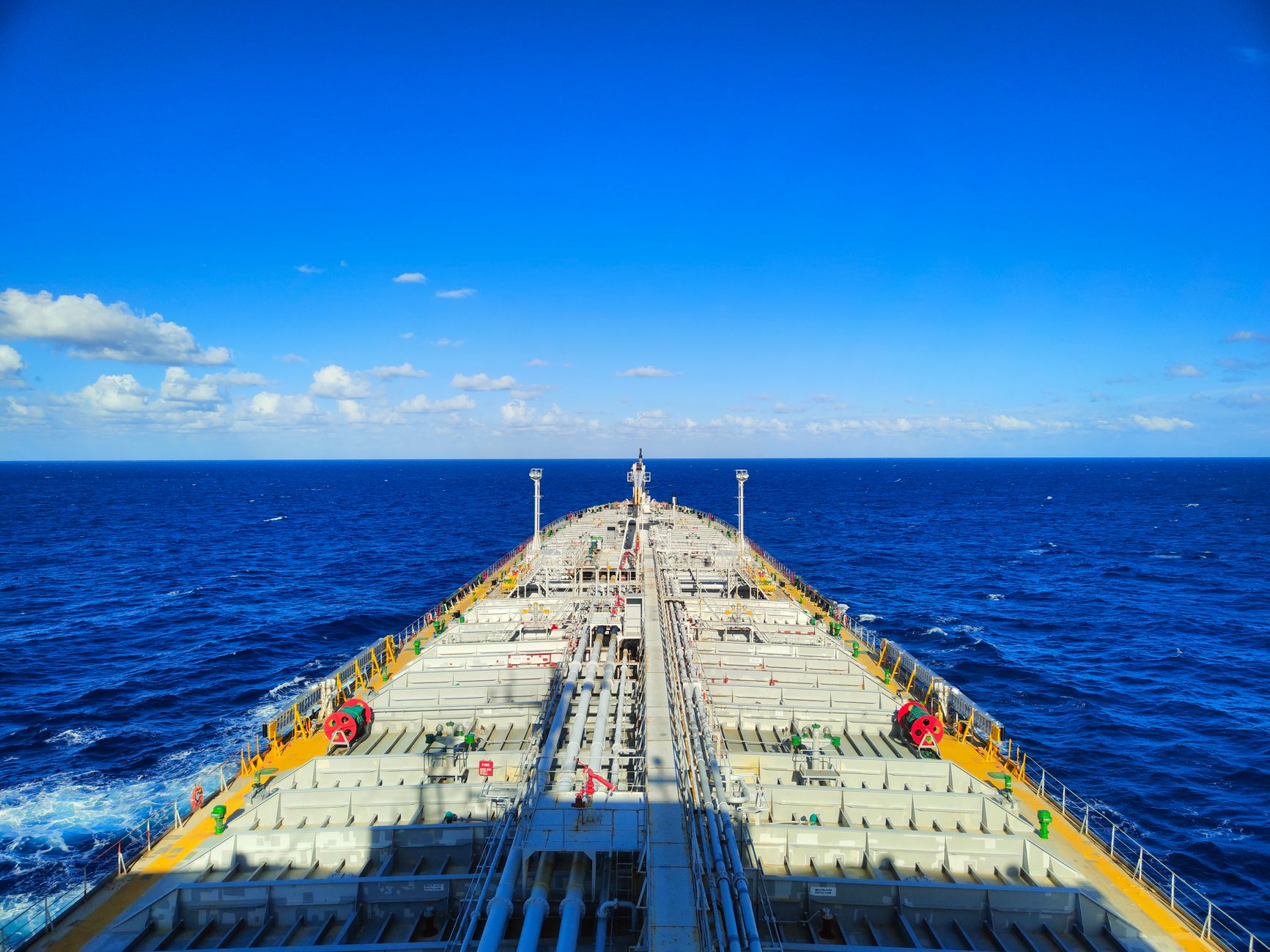 aerial view of oil tankers navigating a narrow strait at dawn, surrounded by calm blue-grey water
