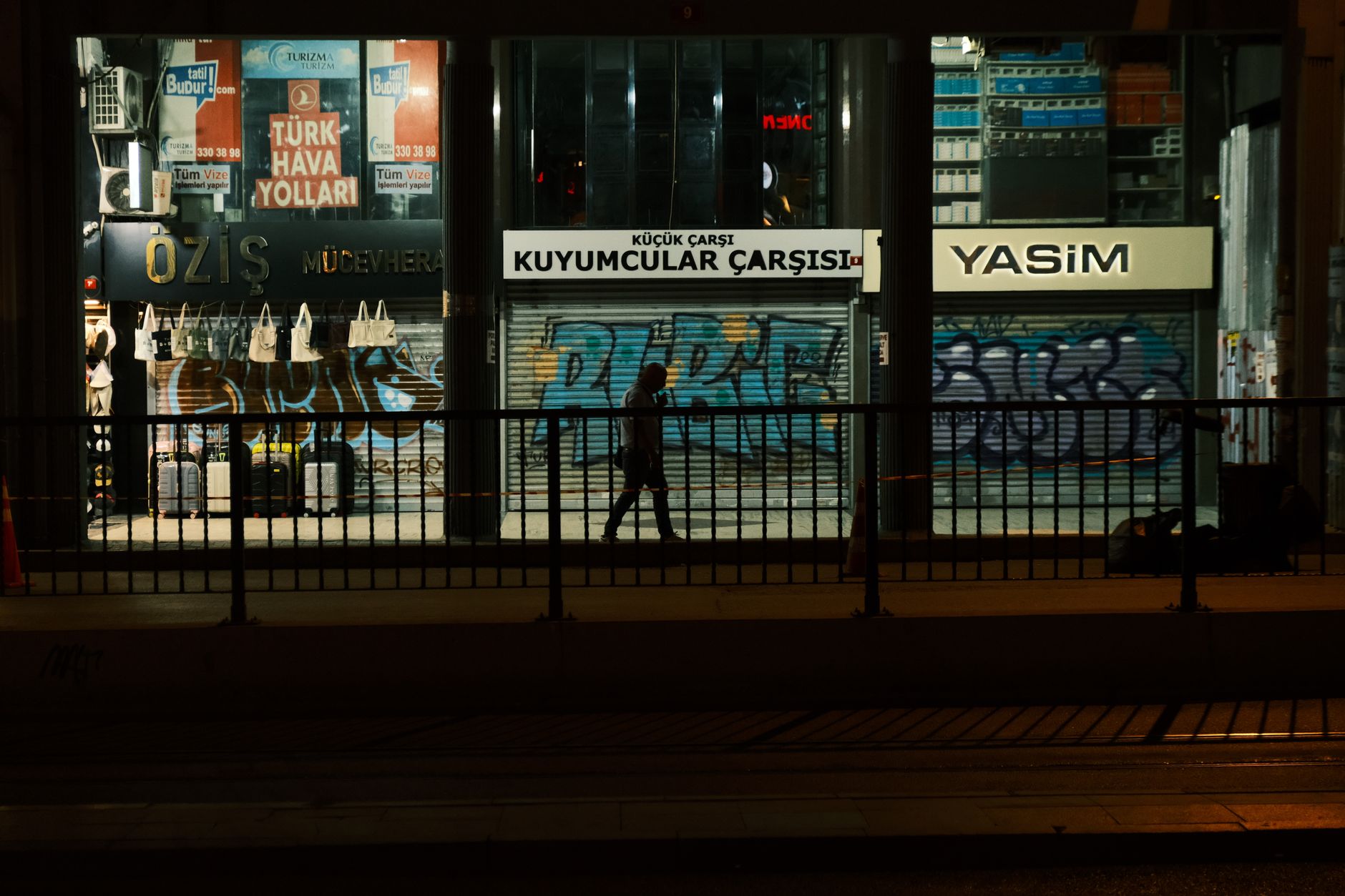 a row of currency exchange storefronts in an urban street with hand-written rate boards displayed in windows, shot from across the road