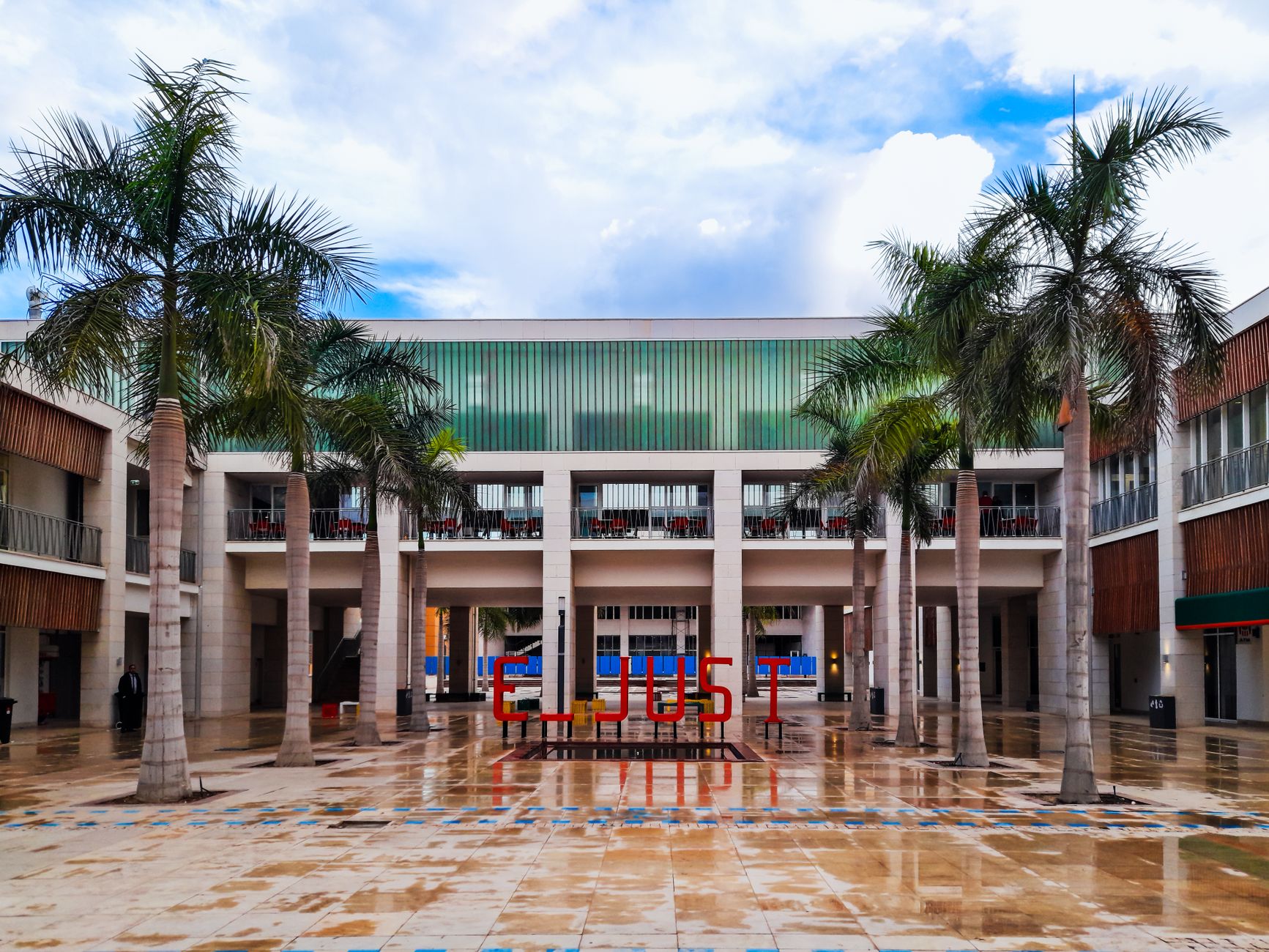 exterior of a modern university research building at dusk, with illuminated laboratory windows and a courtyard plaza