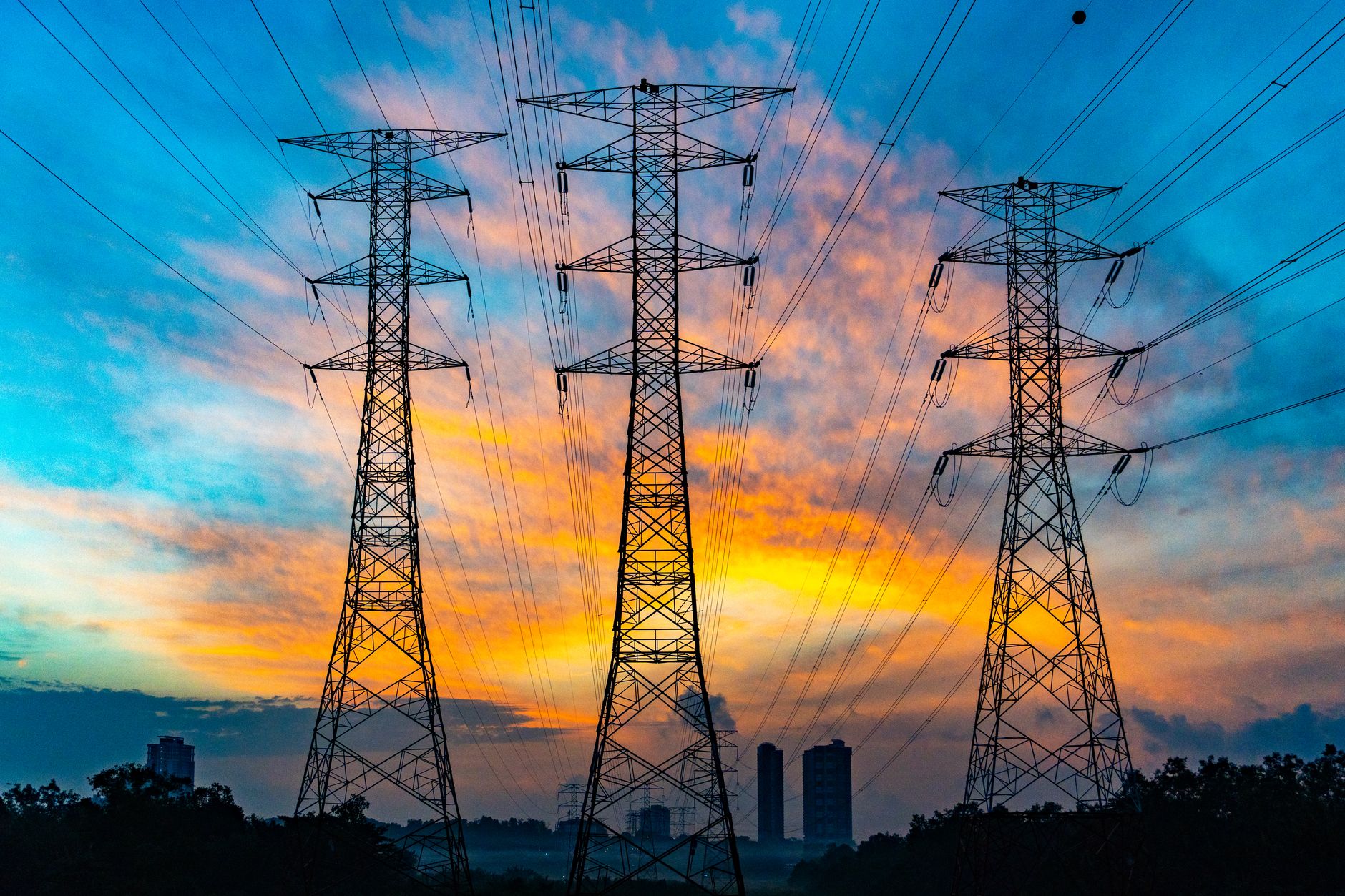 aerial view of a large industrial electricity substation surrounded by transmission towers in a desert landscape at dusk