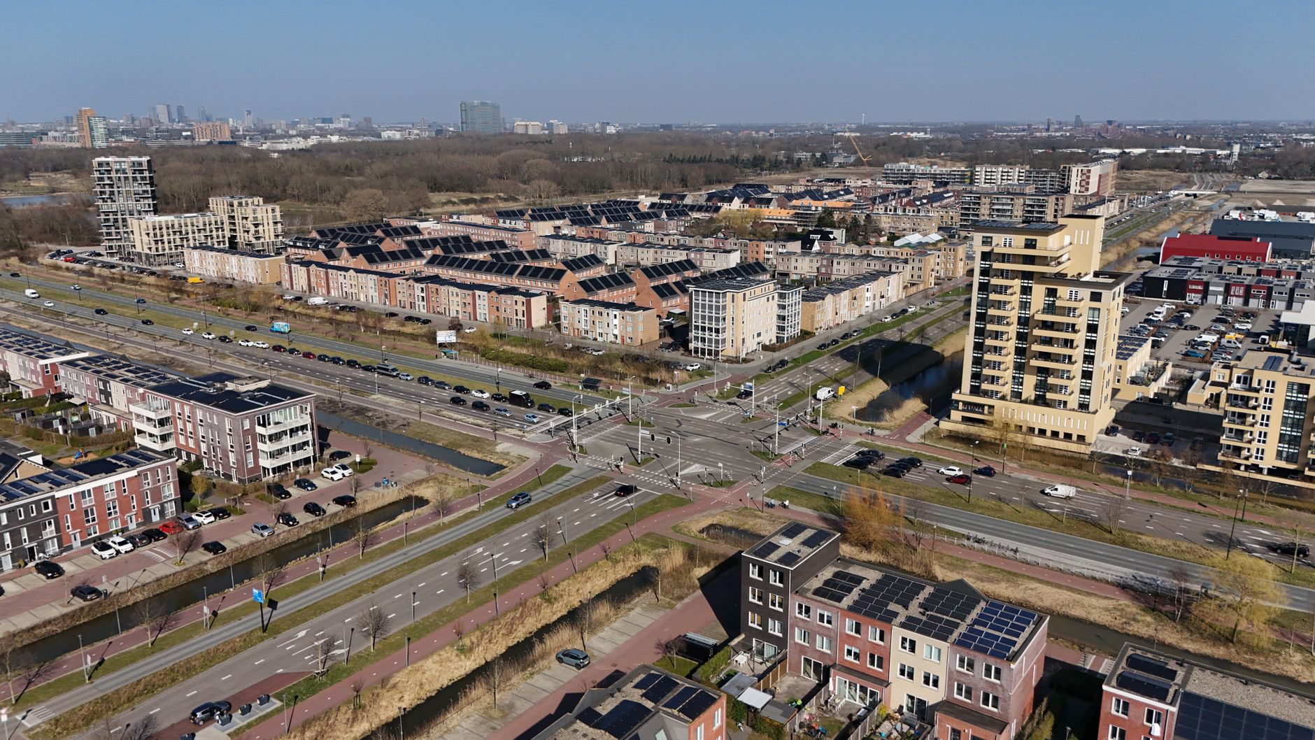 aerial view of a modern technology park with low-rise glass office buildings and solar panels visible on rooftops, set against a clear sky