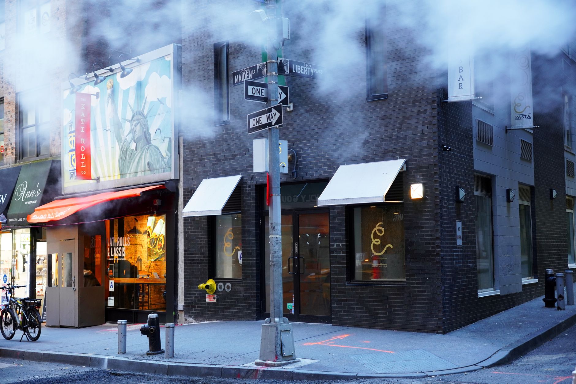 row of fast-casual restaurant storefronts along an American urban street with pedestrians passing, photographed from across the road