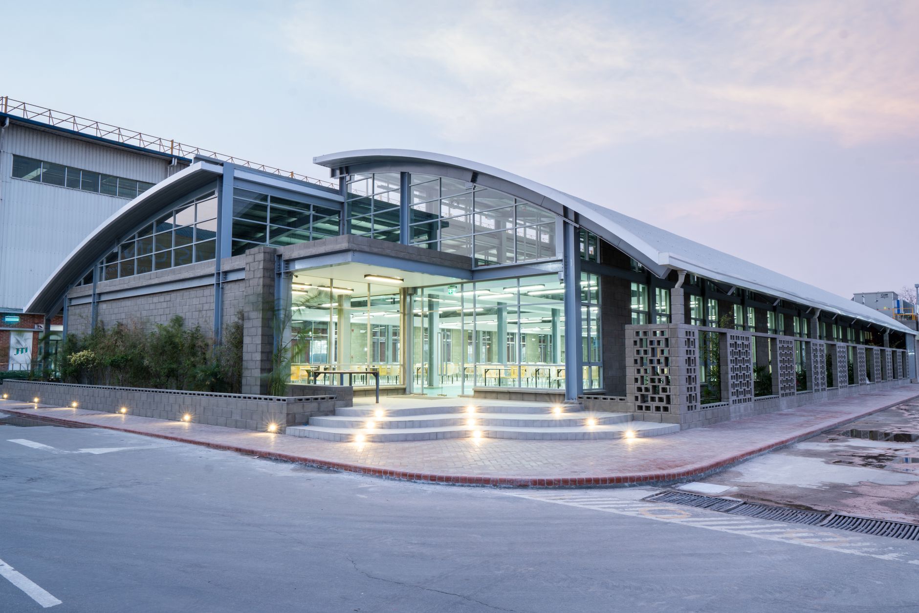 exterior of a mid-sized corporate office building in an Israeli industrial zone, with security cameras mounted above the entrance and a modest parking area in the foreground