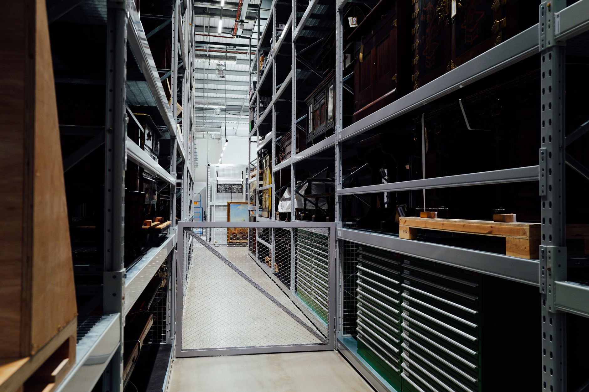rows of stainless steel cookware and kitchen tools arranged on warehouse shelving in a large distribution facility