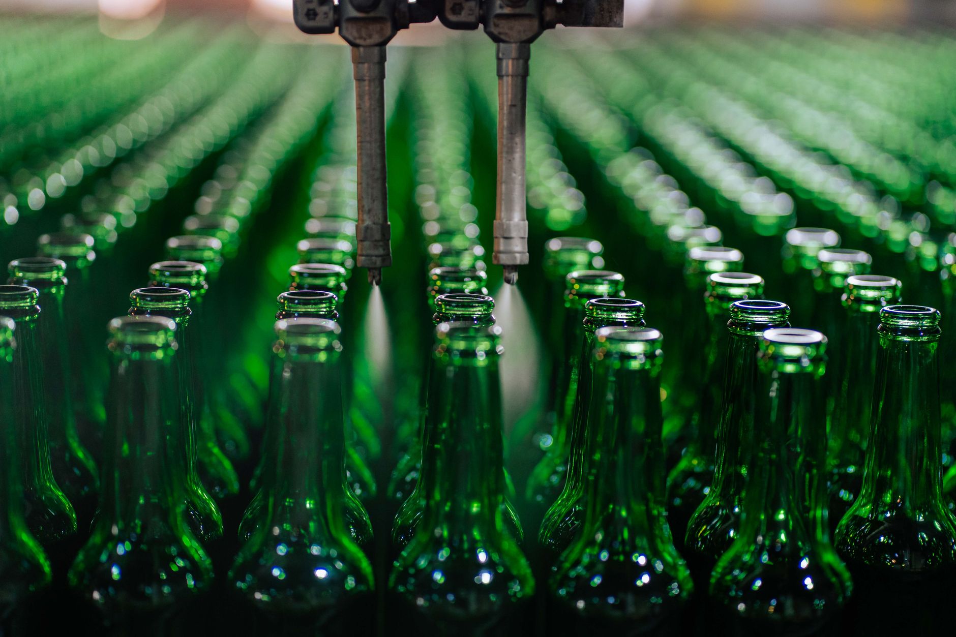 rows of industrial robotic arms positioned along an automated assembly line in a modern factory, photographed from a wide overhead angle