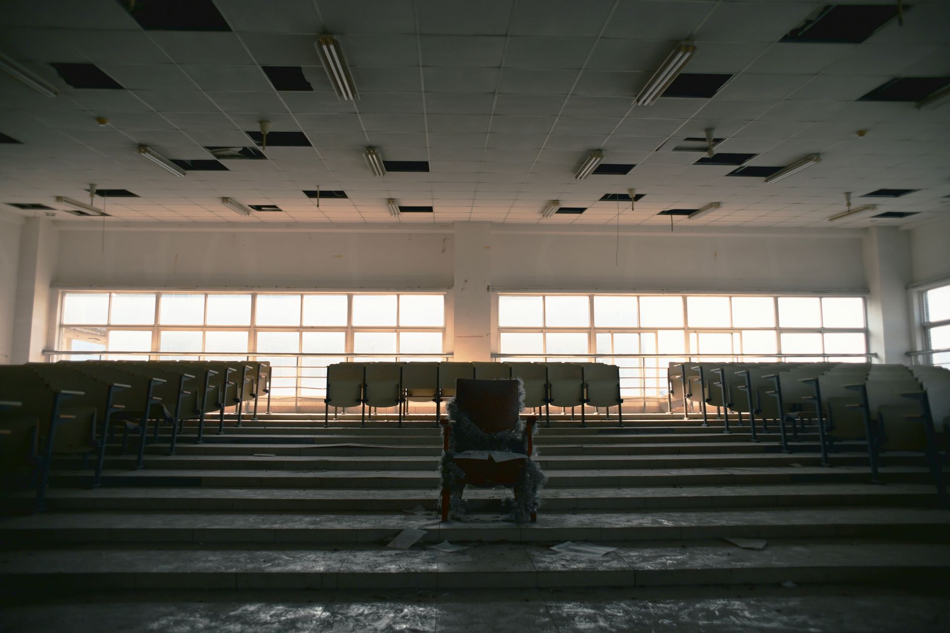 rows of empty folding chairs arranged inside a large community center gymnasium with Michigan state flags visible on the walls