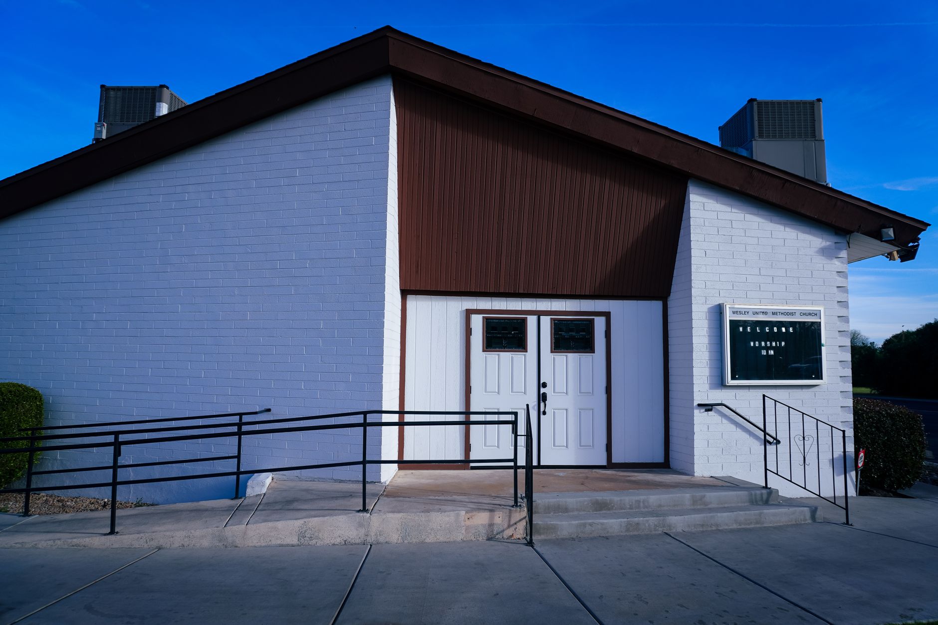 exterior of a modern freestanding emergency hospital building in a suburban Texas setting at midday, with a clear blue sky overhead