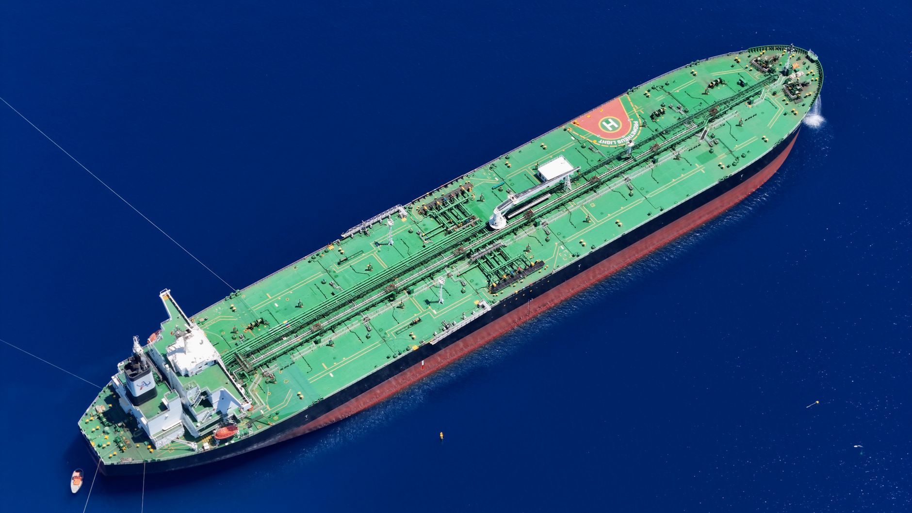 aerial view of oil tankers anchored in calm Persian Gulf waters near a coastal refinery complex at dawn