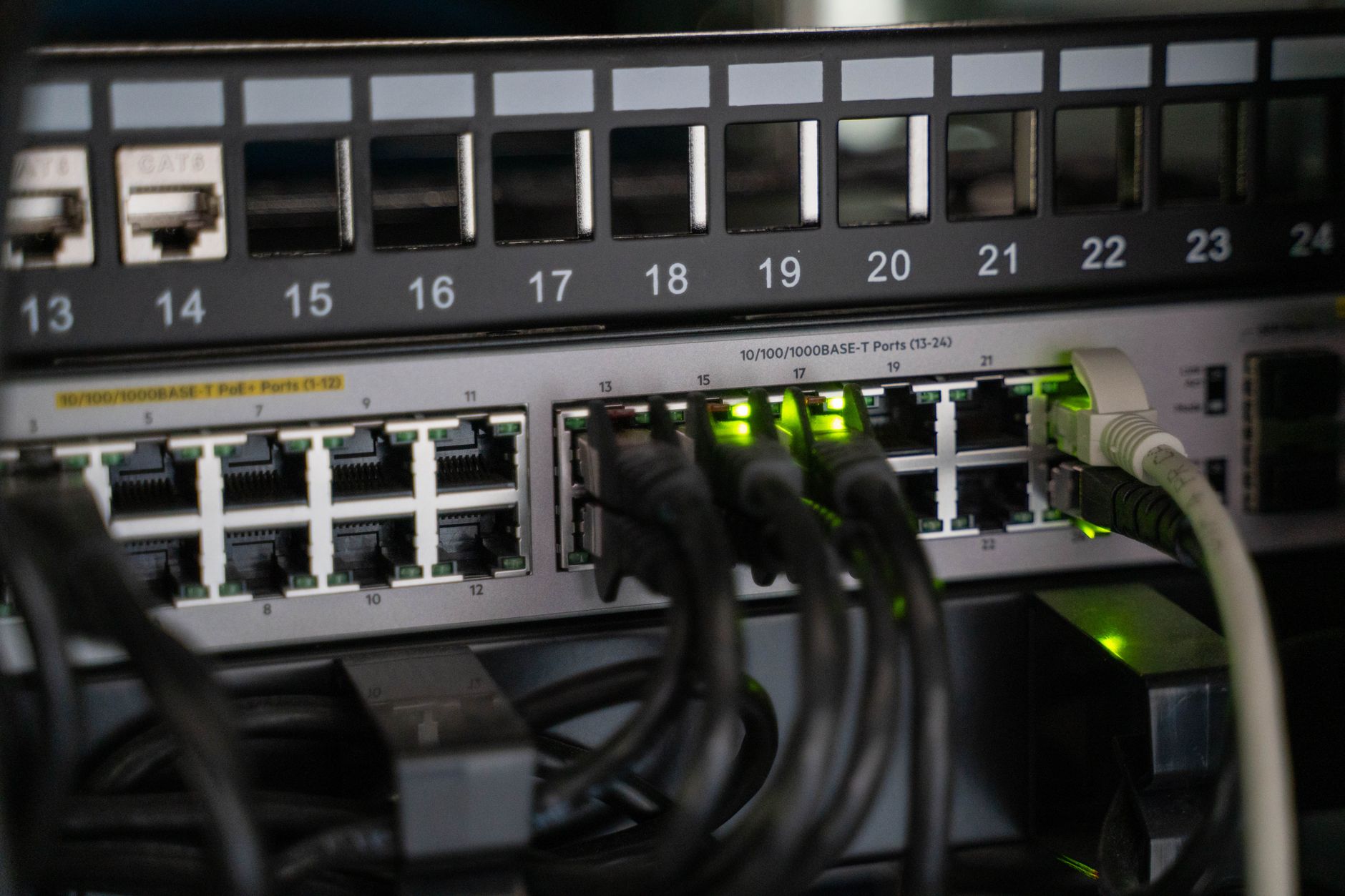 close-up of server rack hardware inside a dimly lit data center, with blinking status lights and dense cable routing visible