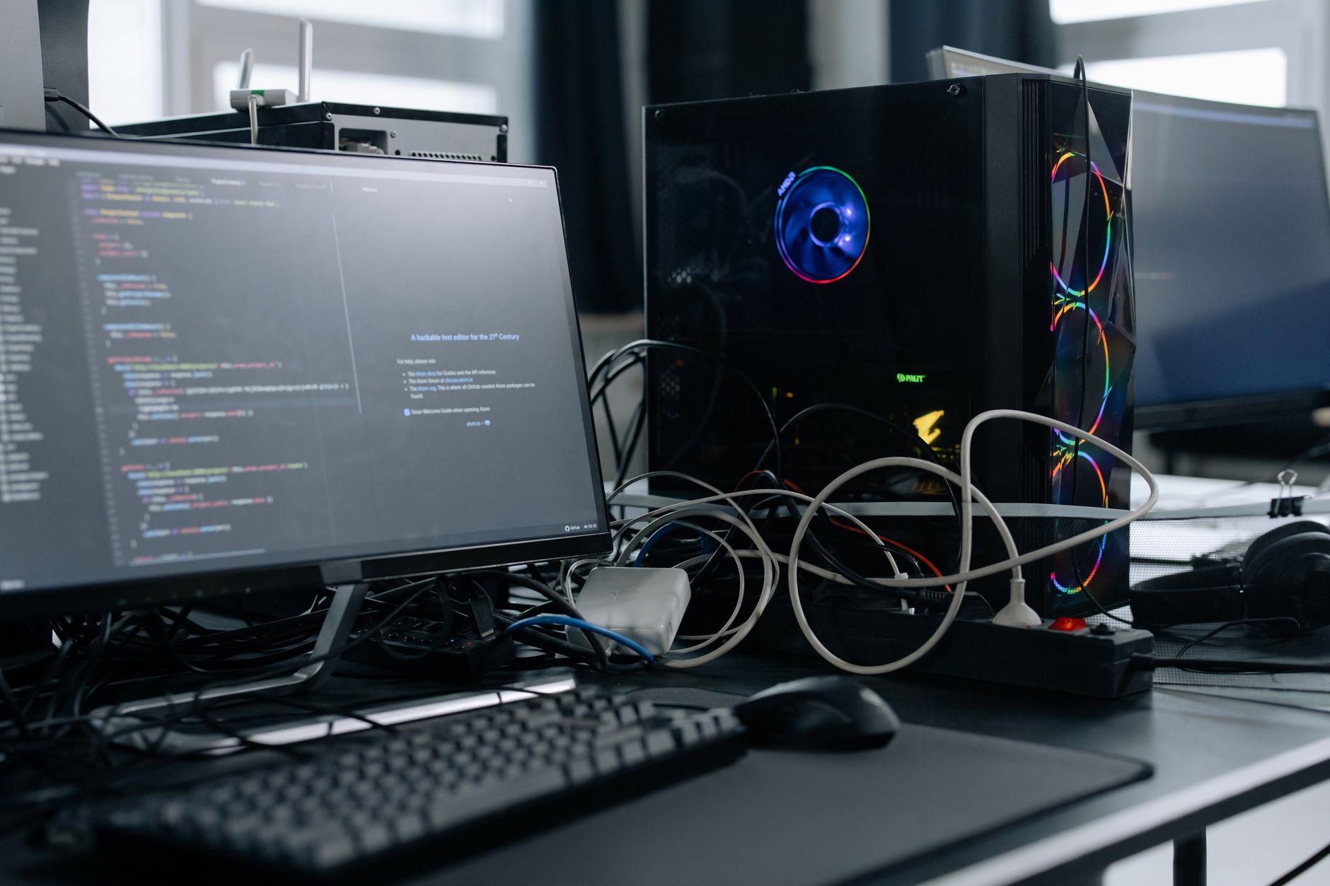 developer workstation displaying lines of code and terminal output on dual monitors in a modern open-plan office environment