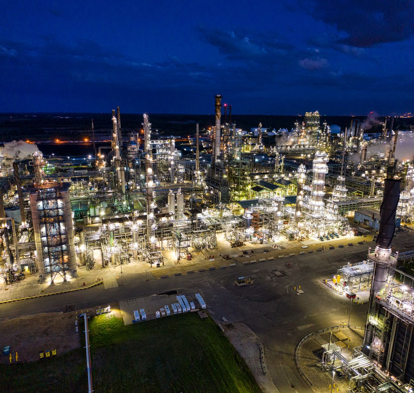 exterior of a large natural gas power plant facility at dusk, with turbine structures and industrial pipelines visible against an orange sky