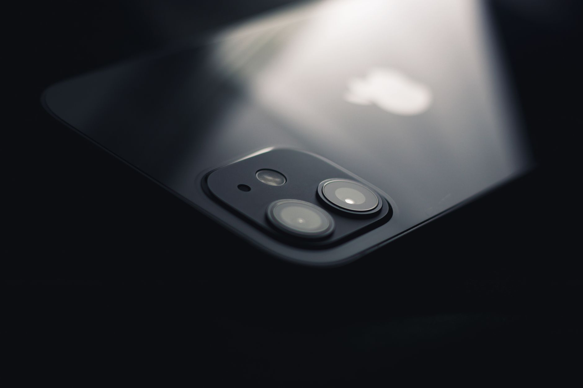 close-up of a high-end smartphone camera module with multiple lenses on a matte black surface, resting on a minimalist desk