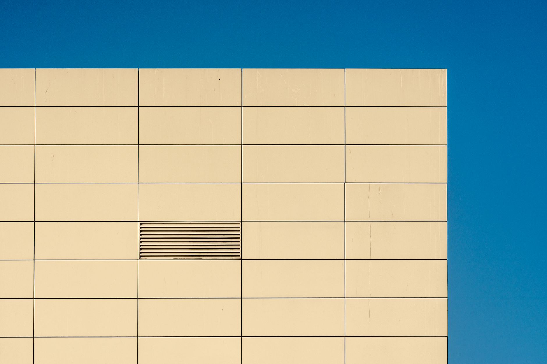 exterior of a modern semiconductor fabrication facility at dusk, with clean-room ventilation stacks visible against an orange sky