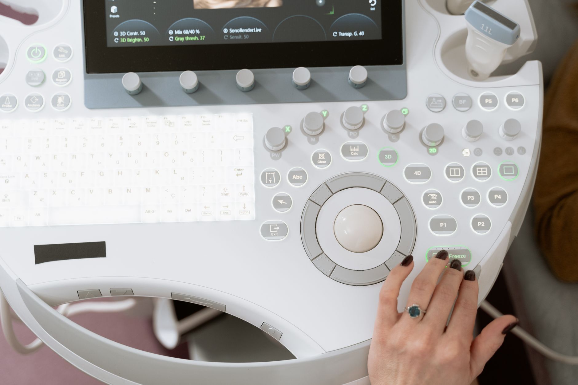 a compact handheld ultrasound probe resting on a clinical examination table in a softly lit medical office, no people in the frame