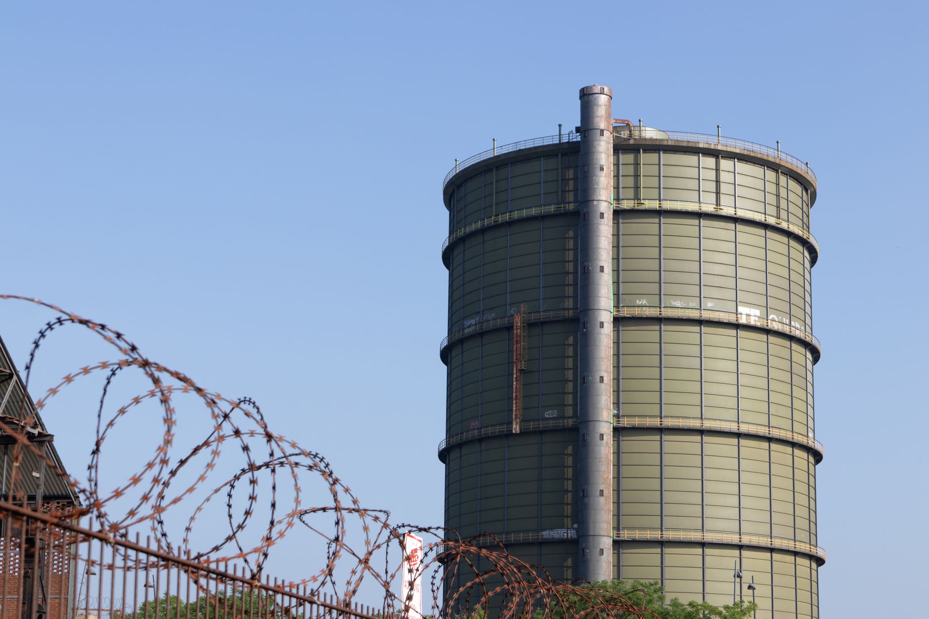 exterior of a large European natural gas storage terminal at dusk, steel tanks and pipeline infrastructure stretching across a flat industrial landscape