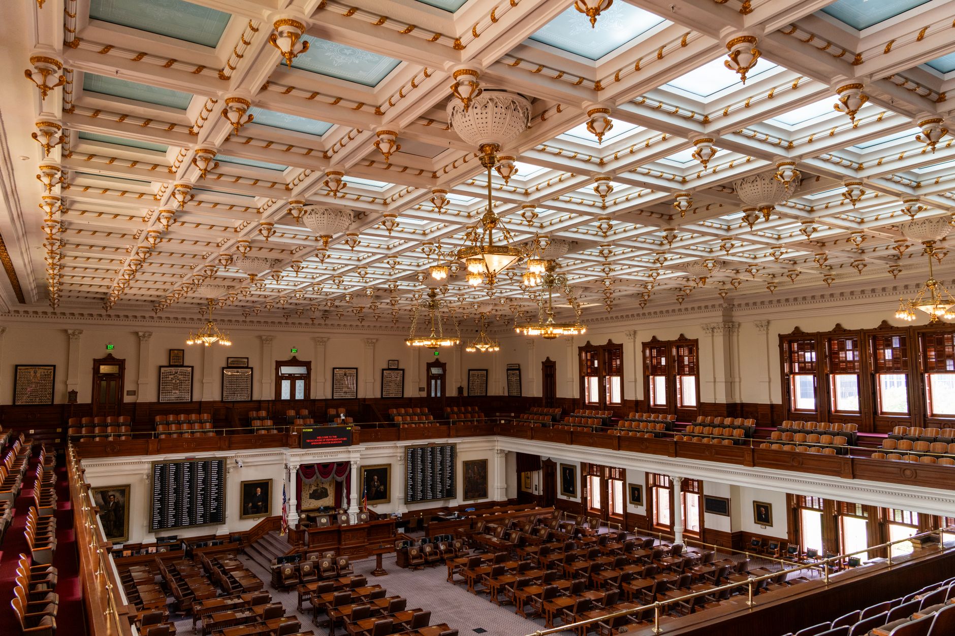 empty chamber of the United States Senate with rows of mahogany desks under warm overhead lighting, no people present