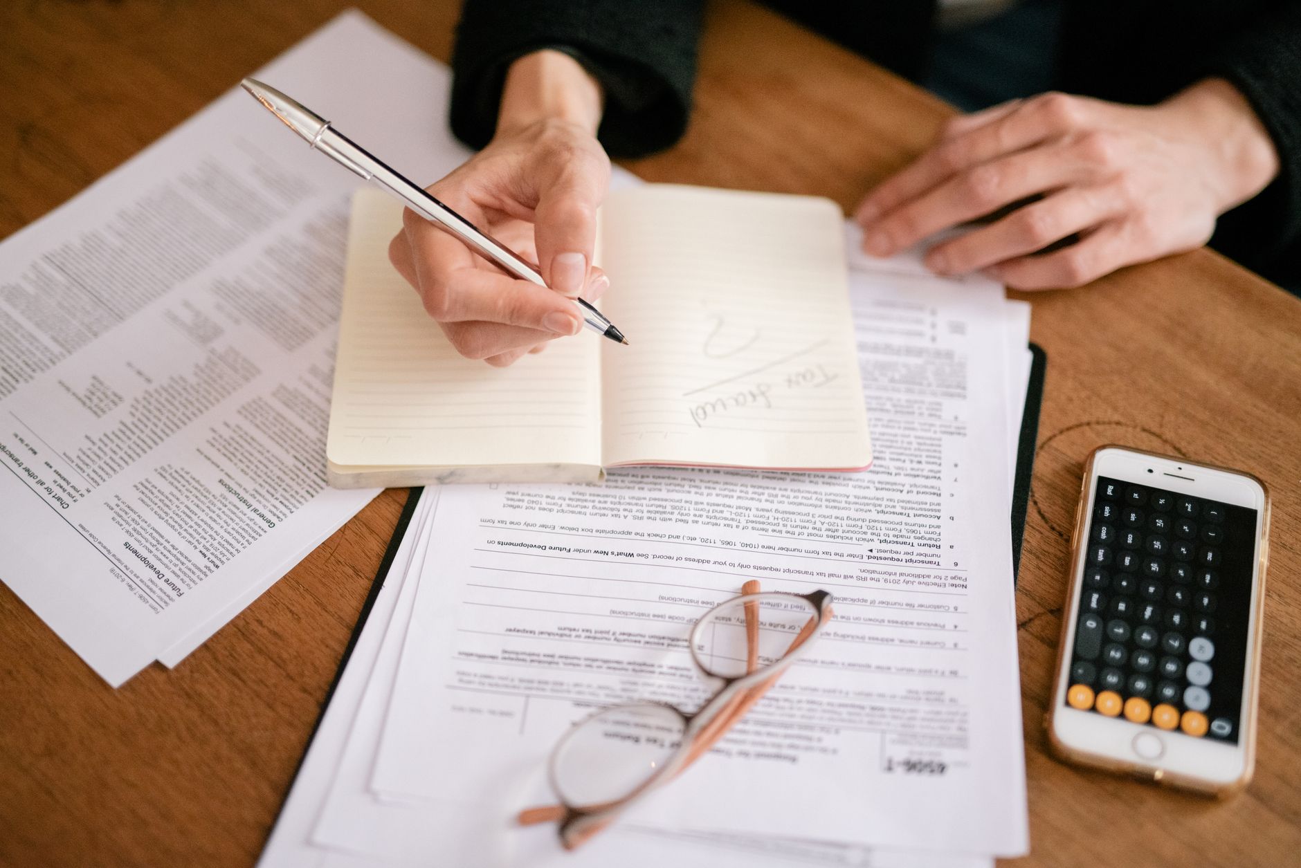 a close-up of a printed tax planning worksheet on a wooden desk alongside a calculator and reading glasses, no faces visible