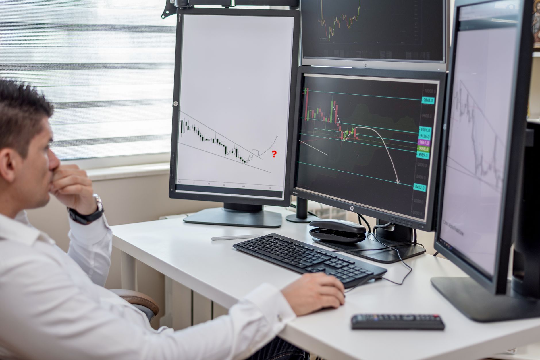 a row of trading terminals inside a large brokerage firm's operations center, displaying cryptocurrency ticker data on multiple screens