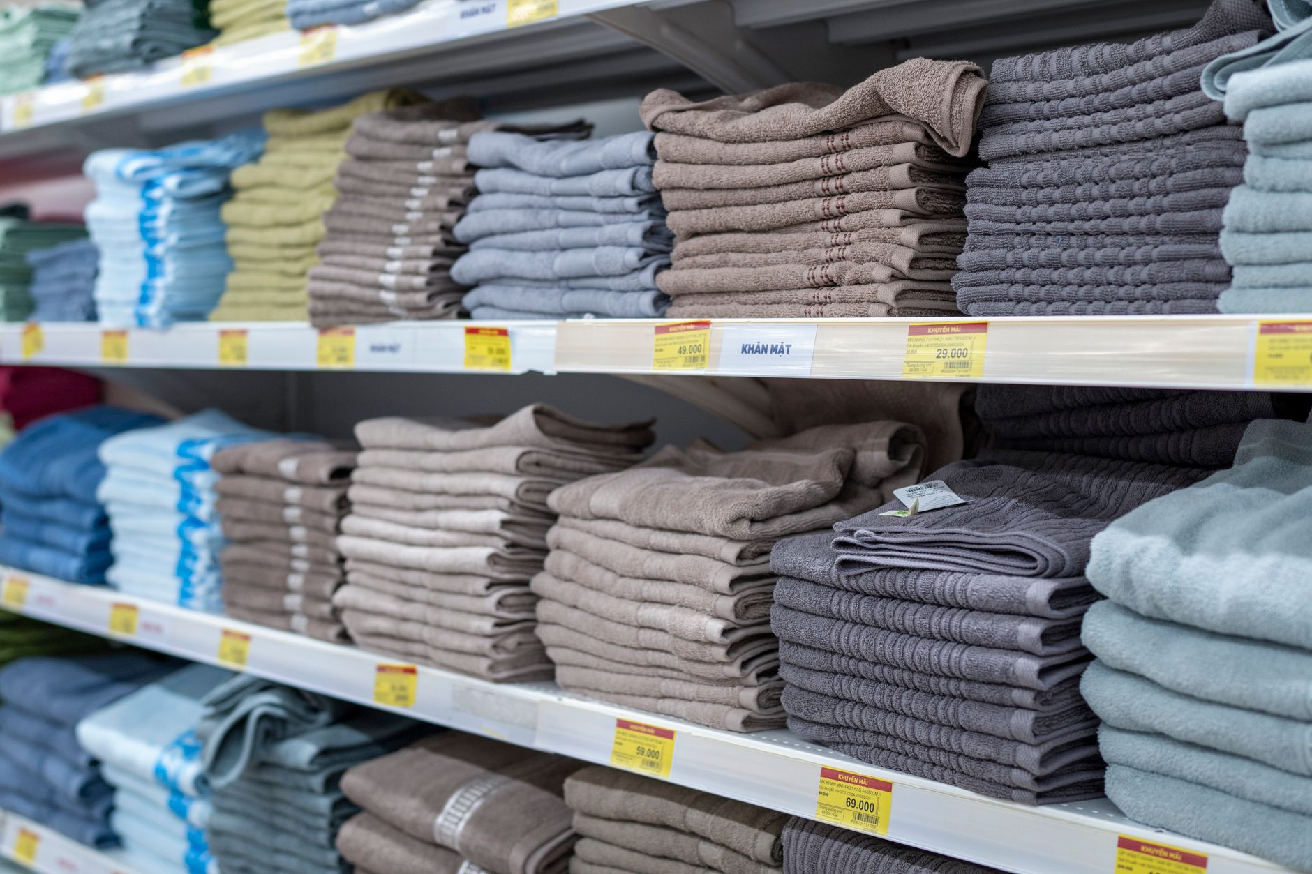neatly arranged rows of folded school blazers and shirts on shelves inside a small community shop, with price tags visible