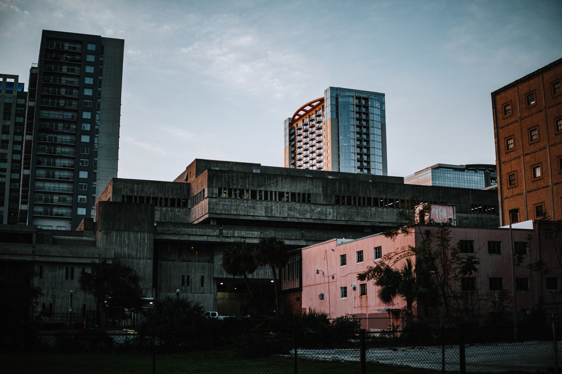 exterior of a cryptocurrency exchange data center building at dusk, with server cooling units visible along a concrete facade under an orange sky