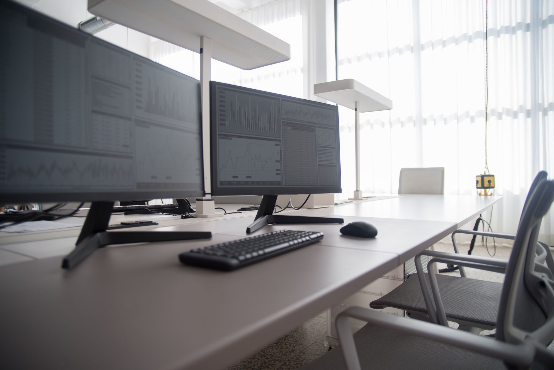 rows of empty open-plan office workstations with abandoned desk accessories and unplugged monitor cables in a modern tech office interior