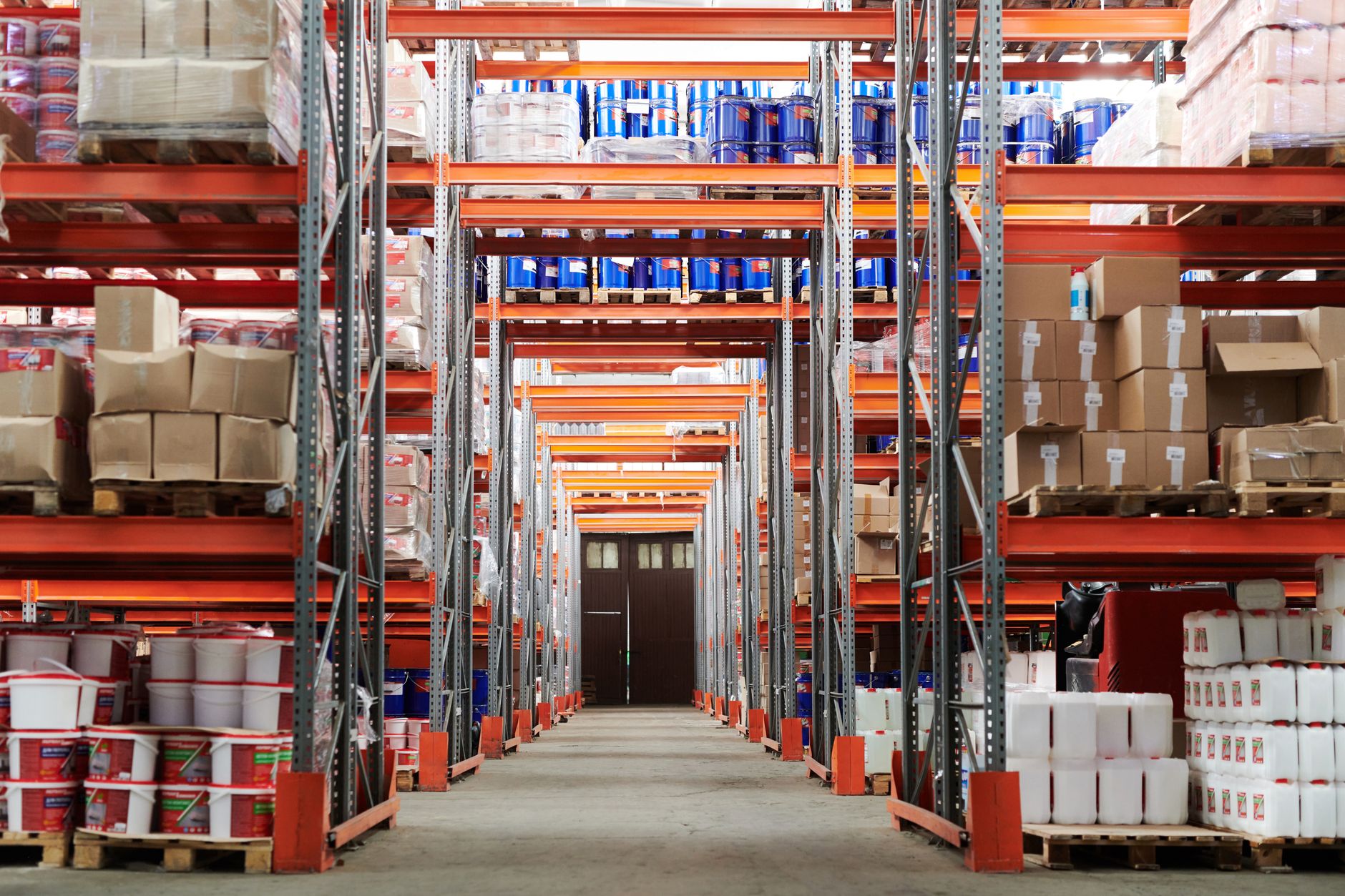 interior of a large retail distribution warehouse with shelving units stacked with boxed imported consumer goods under industrial lighting