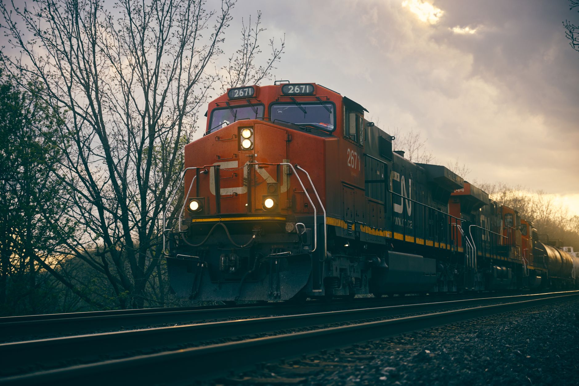 a cargo freight train loaded with steel coils crossing a bridge at the US-Canada border under an overcast sky