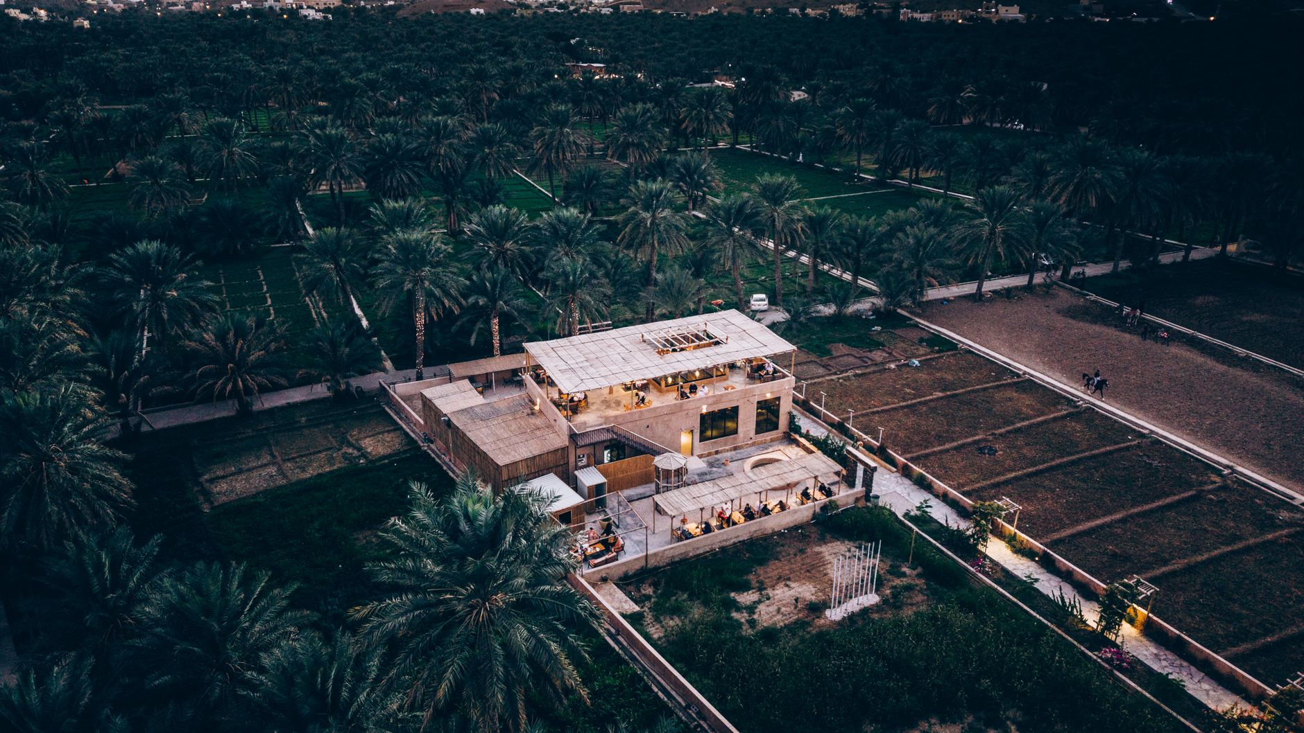 aerial view of a diplomatic conference facility surrounded by desert landscape, with formal meeting rooms visible through glass facades