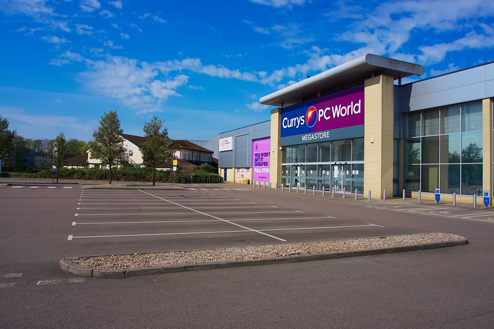 exterior of a mid-sized American retail shopping center with partially empty parking lot under overcast afternoon sky