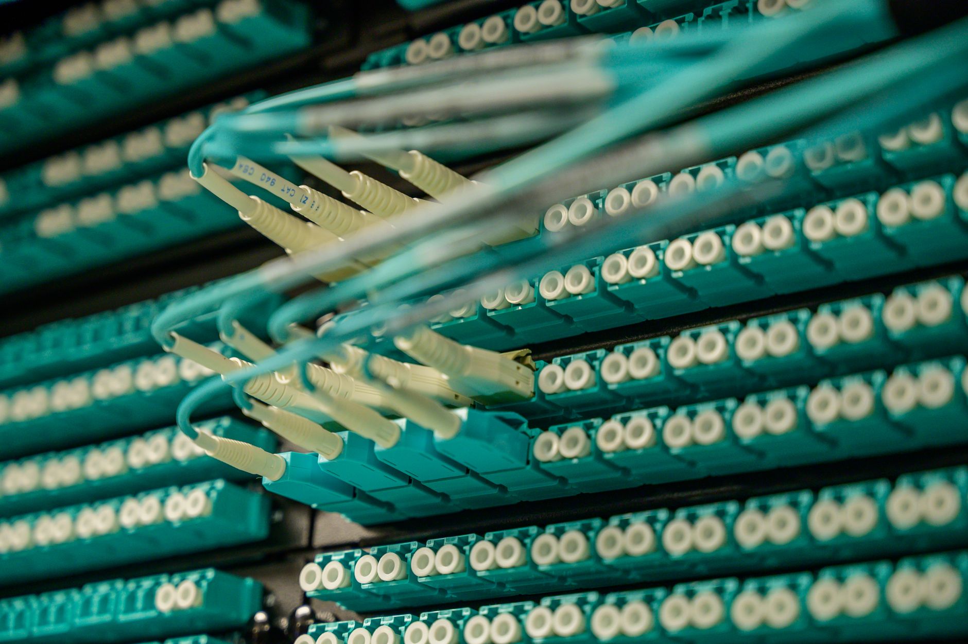 rows of high-frequency trading terminals in a darkened server room, with blinking status lights and cable bundles running along raised floor panels