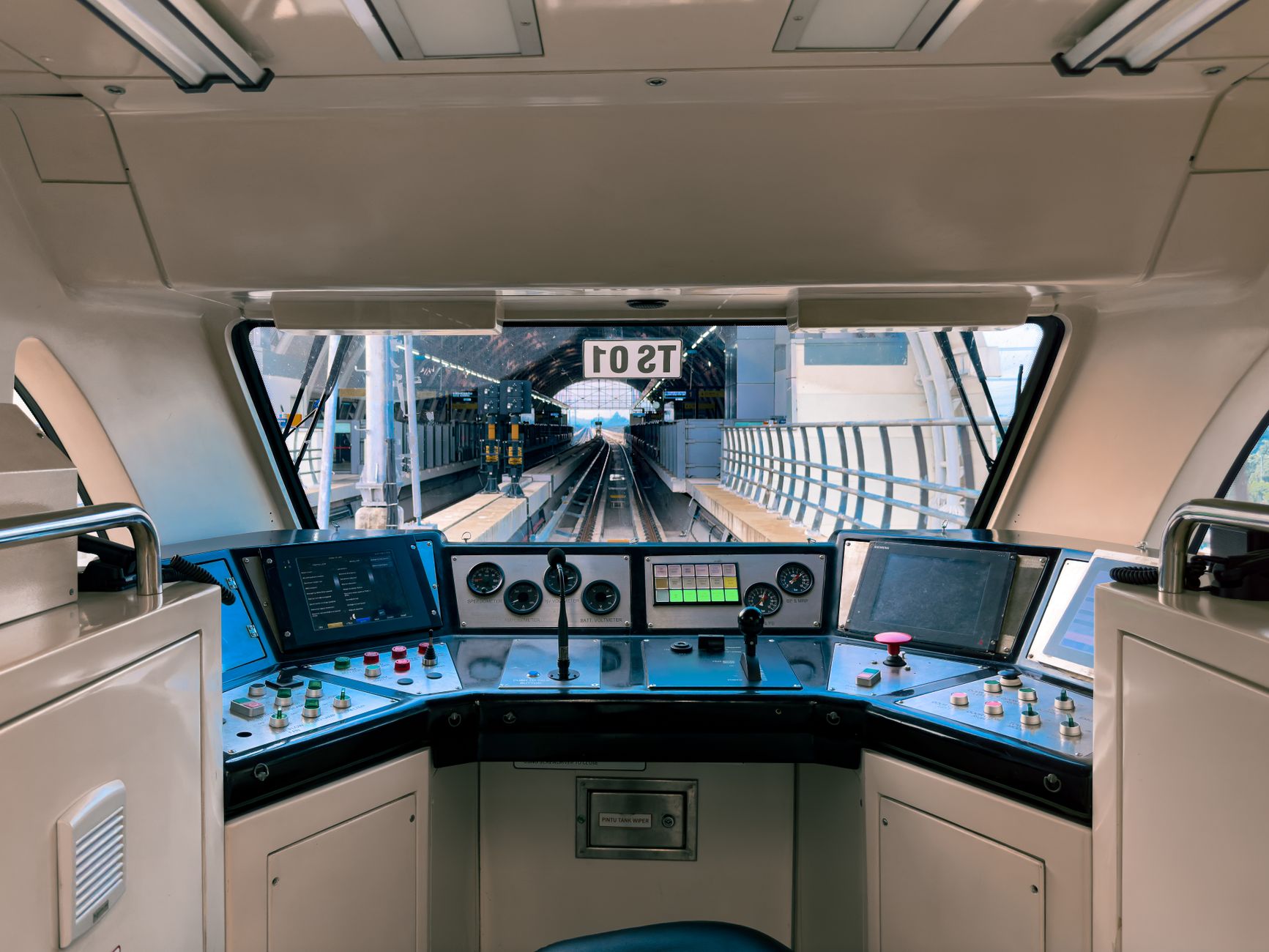 Interior view of a modern ride-hailing operations control centre with large wall-mounted screens displaying city grid maps and live vehicle tracking data, workstations in the foreground