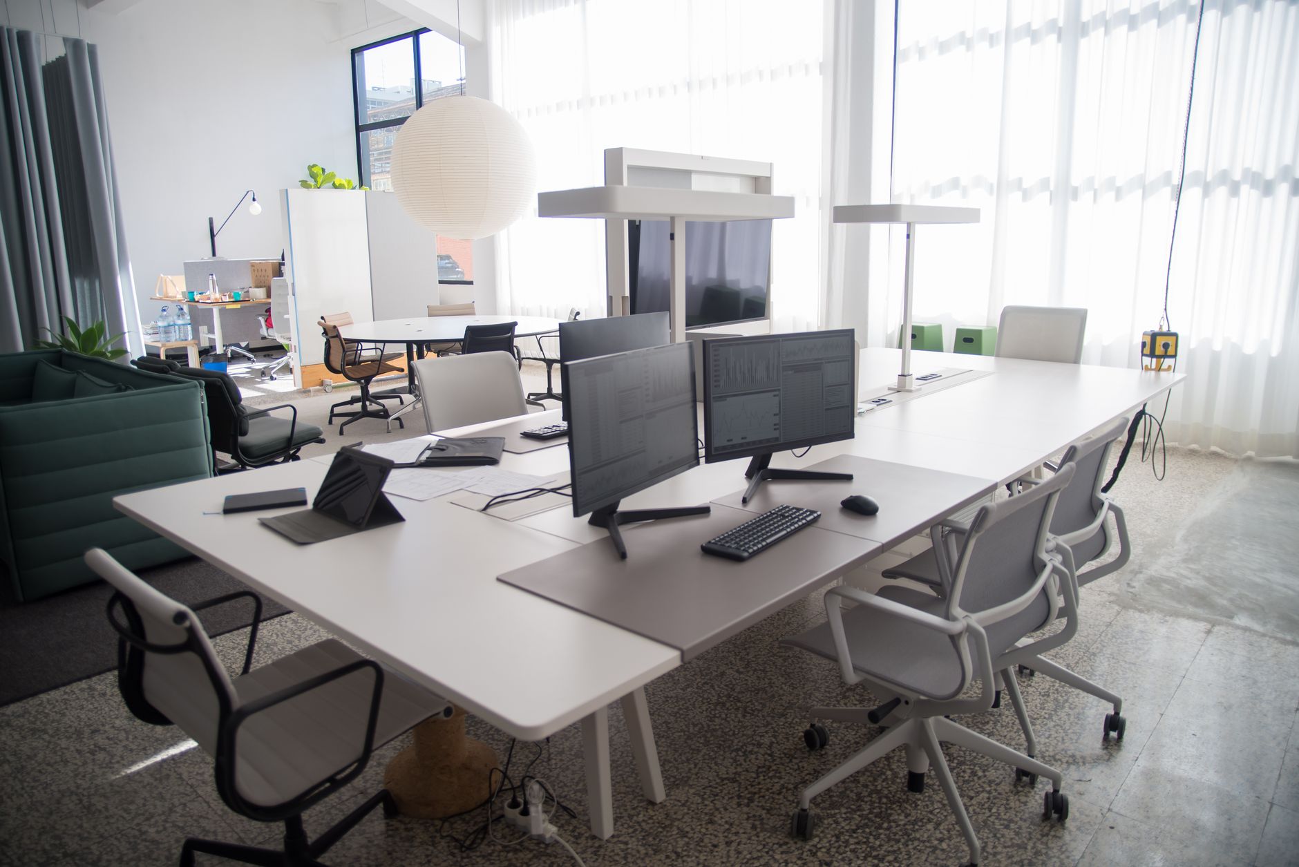 empty open-plan office space with vacant desks and dormant computer monitors in diffused natural light