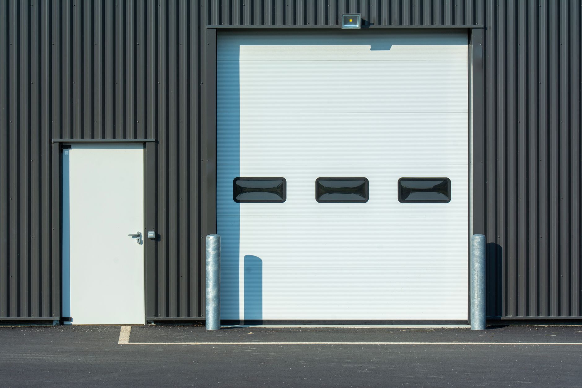exterior view of a large corporate logistics warehouse with a nearly empty parking lot on a grey overcast morning