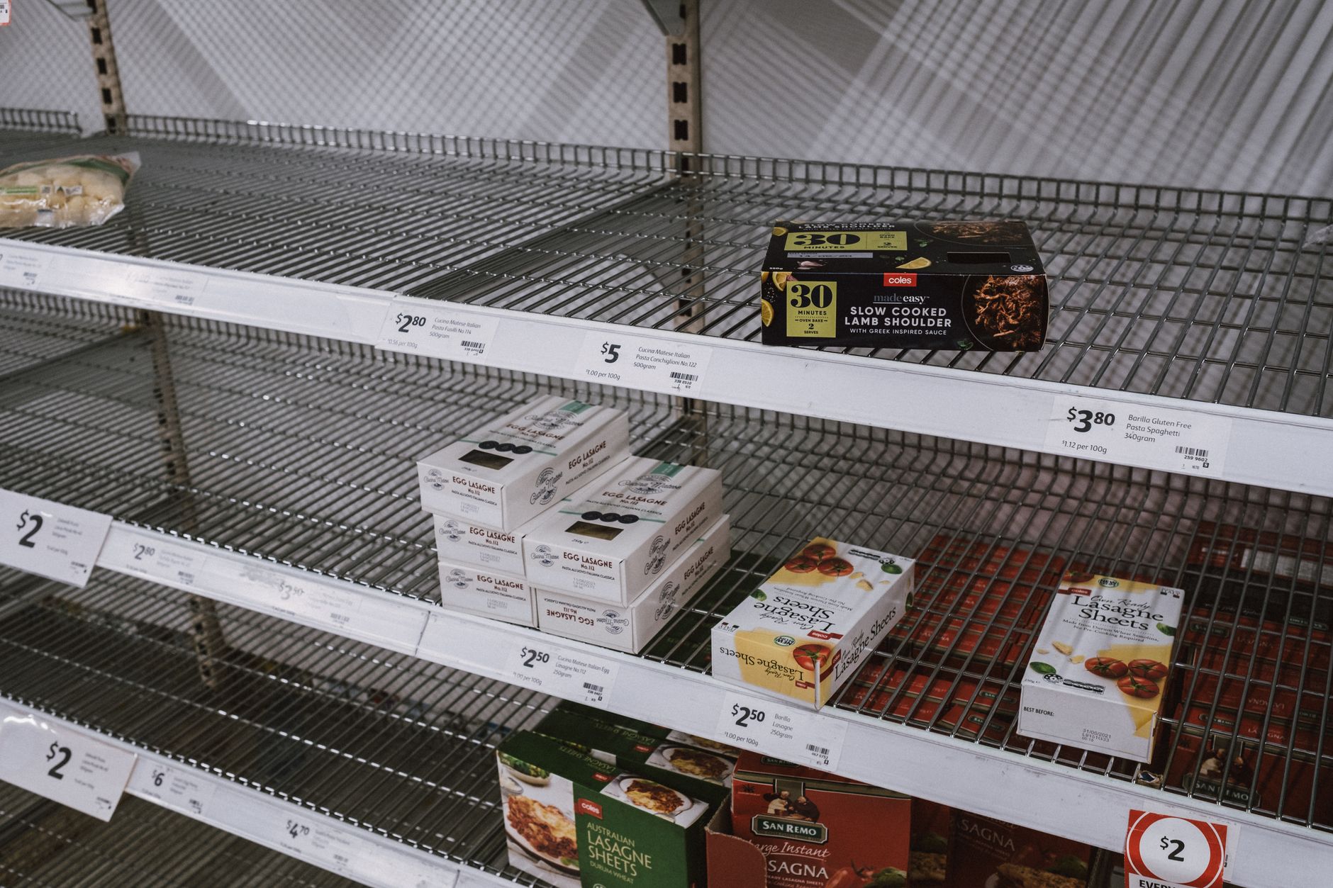 interior of a large retail department store with sparsely filled shopping carts near half-stocked shelves under fluorescent lighting