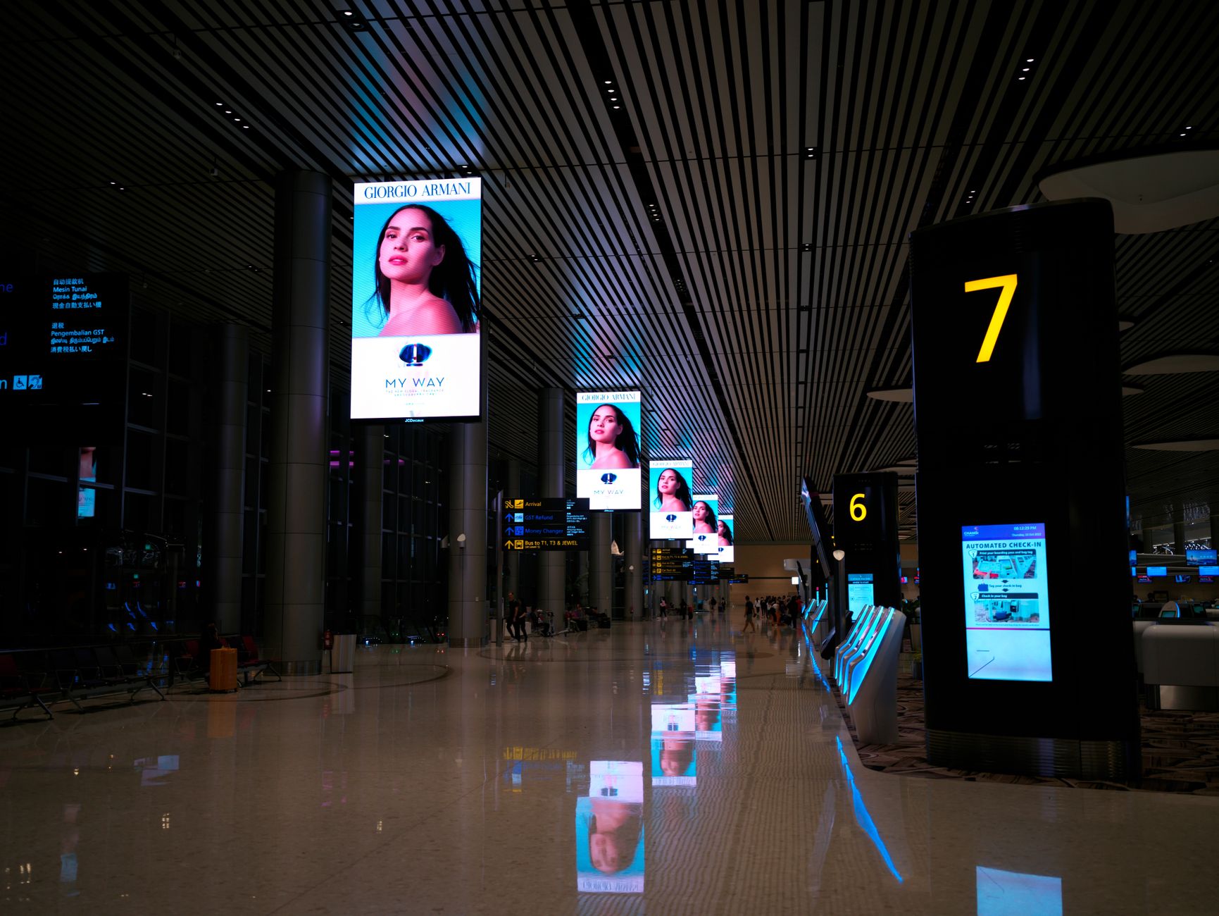 rows of currency exchange kiosks in a Southeast Asian airport terminal, displaying exchange rate boards with figures, no people as focal point