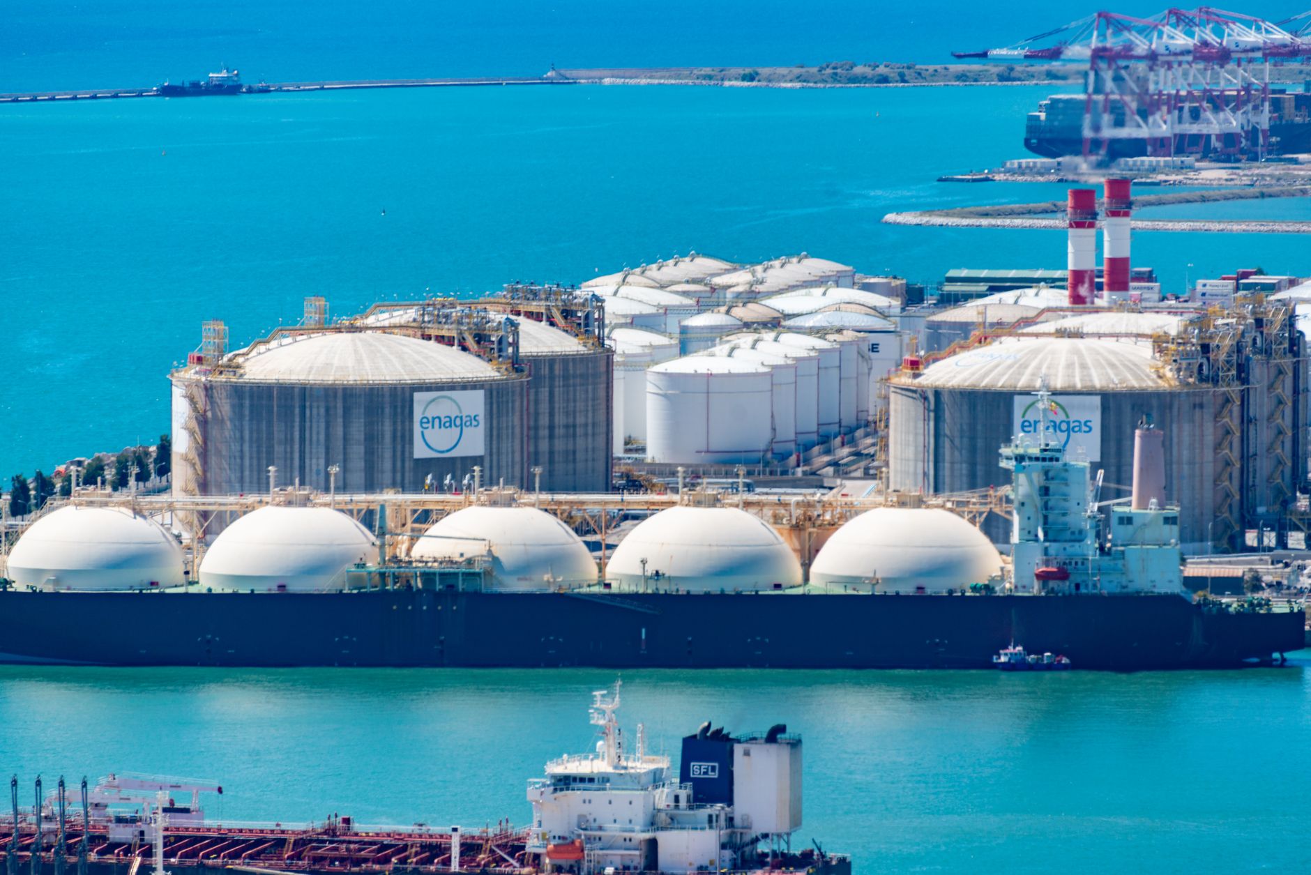 rows of industrial fuel storage tanks inside a Vietnamese petrochemical facility, viewed from an elevated angle