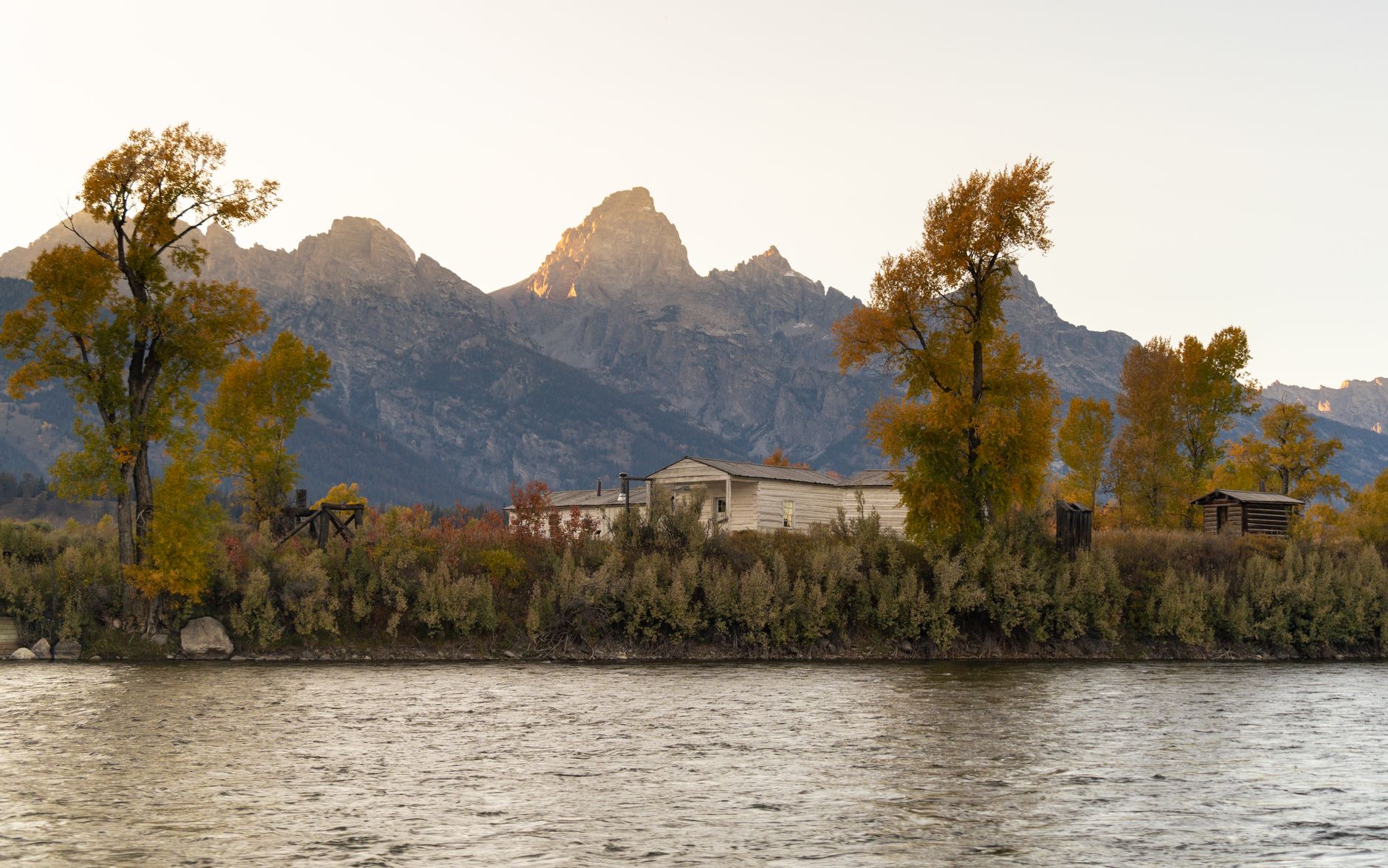 wide-angle exterior shot of the Jackson Lake Lodge conference venue at Jackson Hole, Wyoming, surrounded by mountain peaks and pine forest at dusk