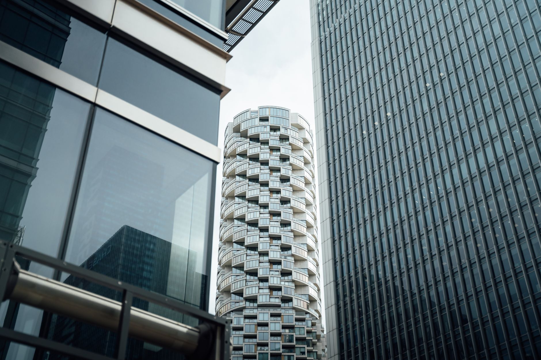 exterior of a glass-fronted venture capital office building in a business district at midday, with city skyline visible in the background