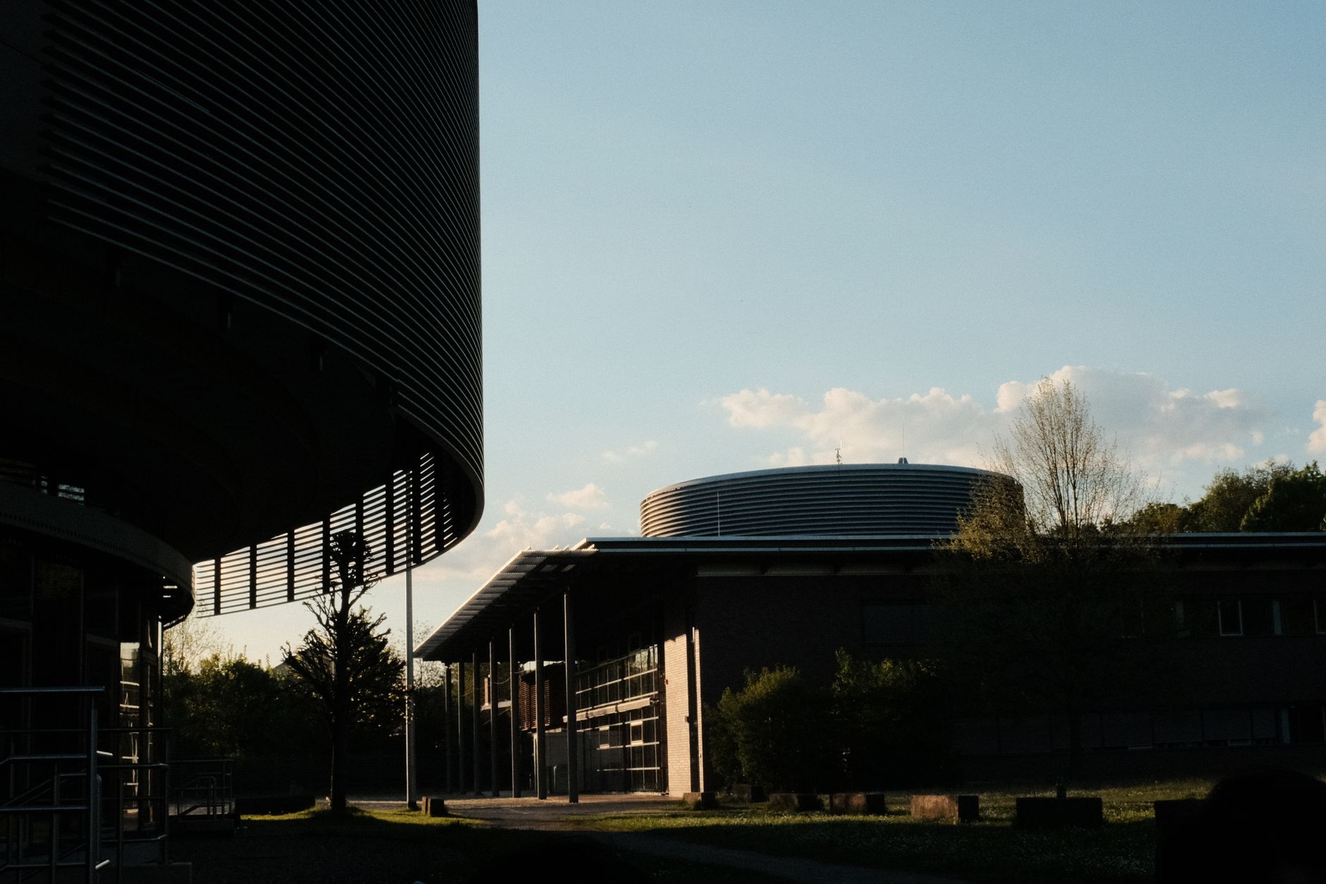 exterior of a modern chip fabrication plant campus at dusk with cooling towers and perimeter lighting visible