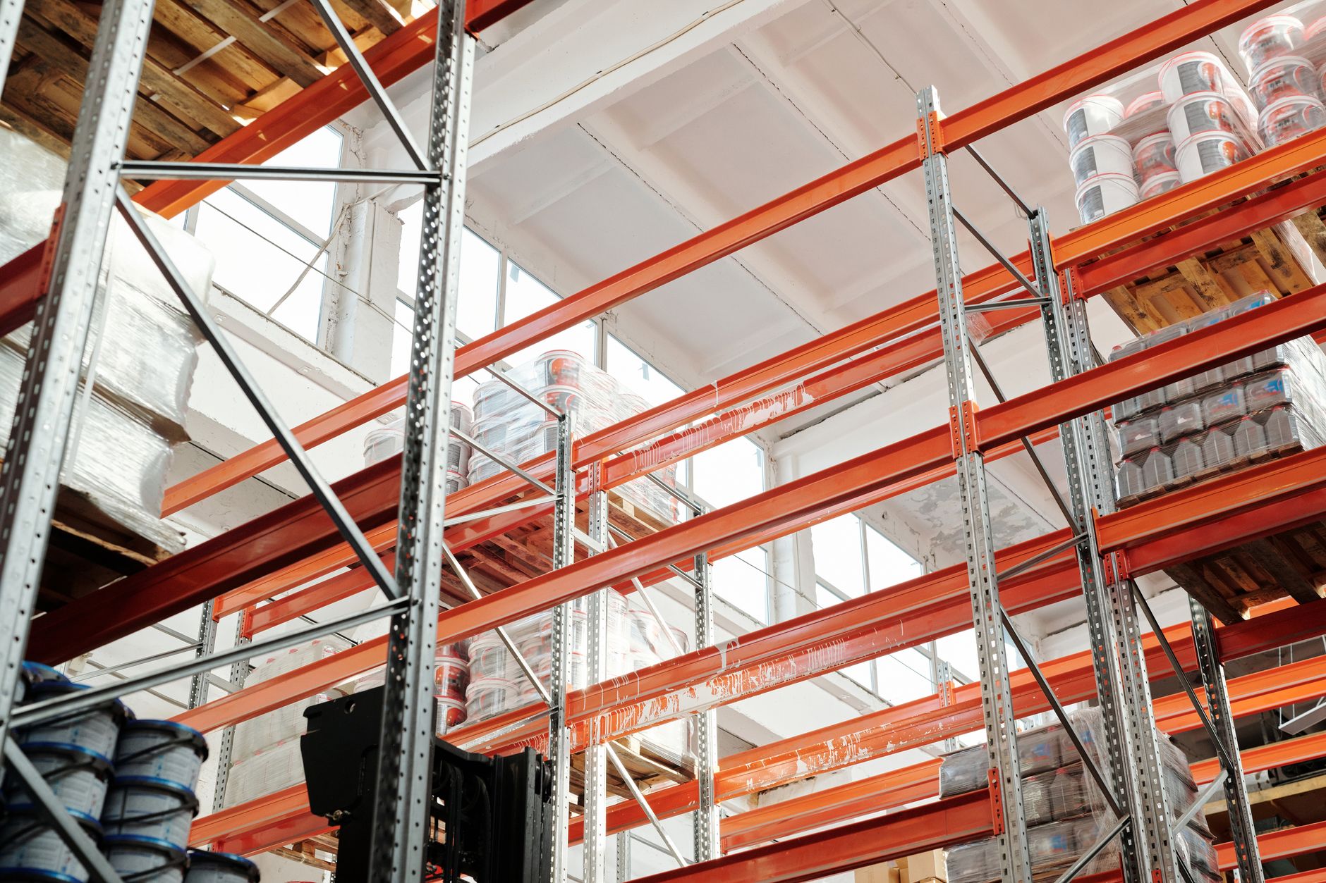 rows of autonomous ground robots staged inside a large industrial warehouse facility with high ceilings and fluorescent overhead lighting