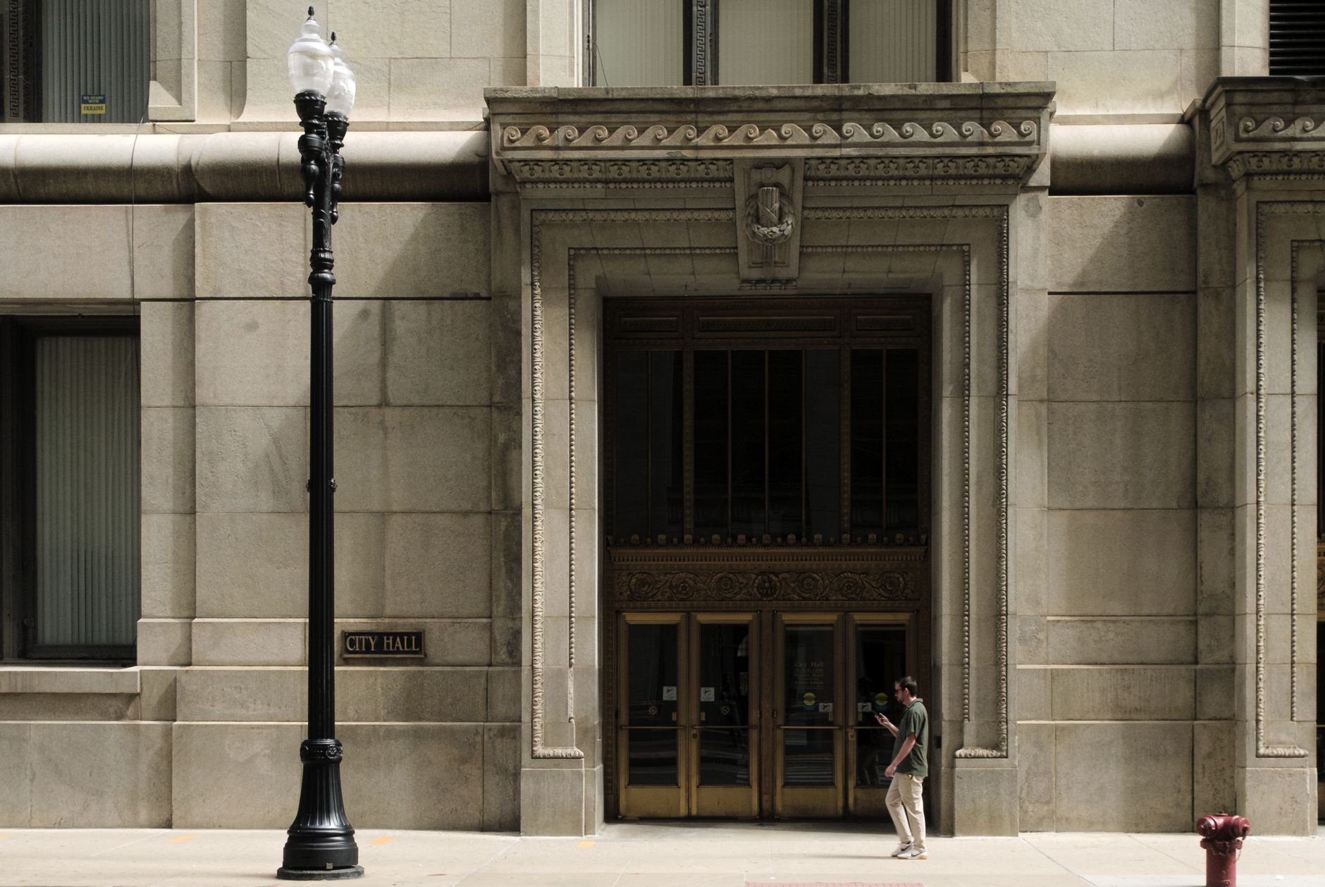 exterior of a neoclassical federal reserve bank building at midday, stone columns and large arched windows visible, an American flag mounted above the entrance, no people prominent in the frame