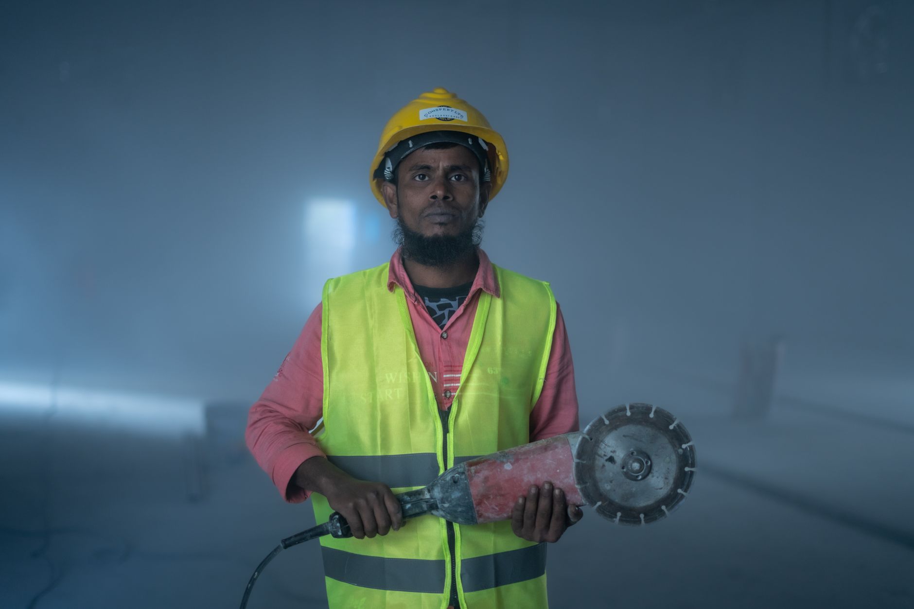 close-up of a construction worker's hard hat with a compact 360-degree camera device mounted to the front, resting on a concrete surface