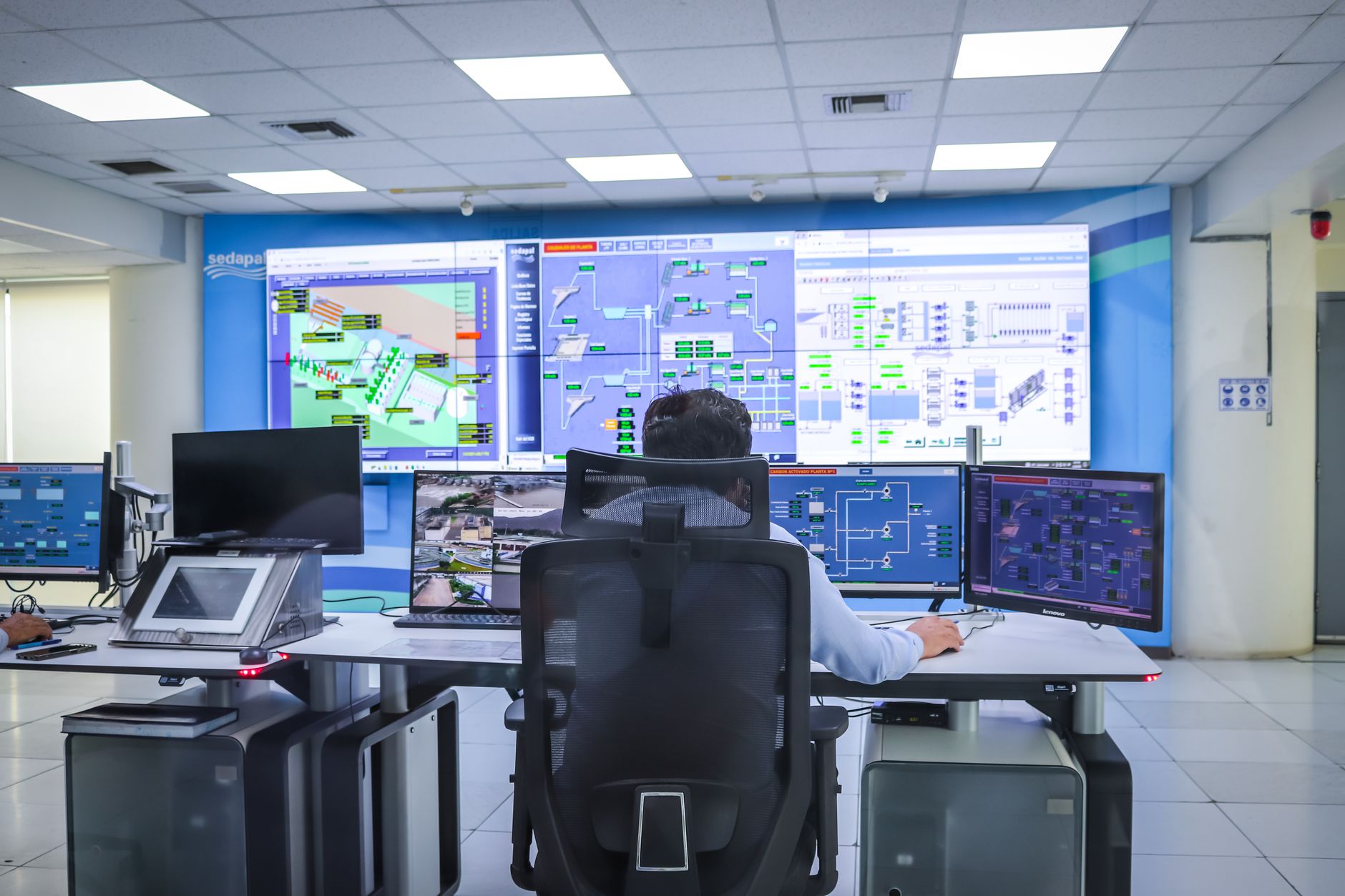 close-up of a cybersecurity operations dashboard on multiple wall-mounted monitors inside a modern network operations center, no visible faces