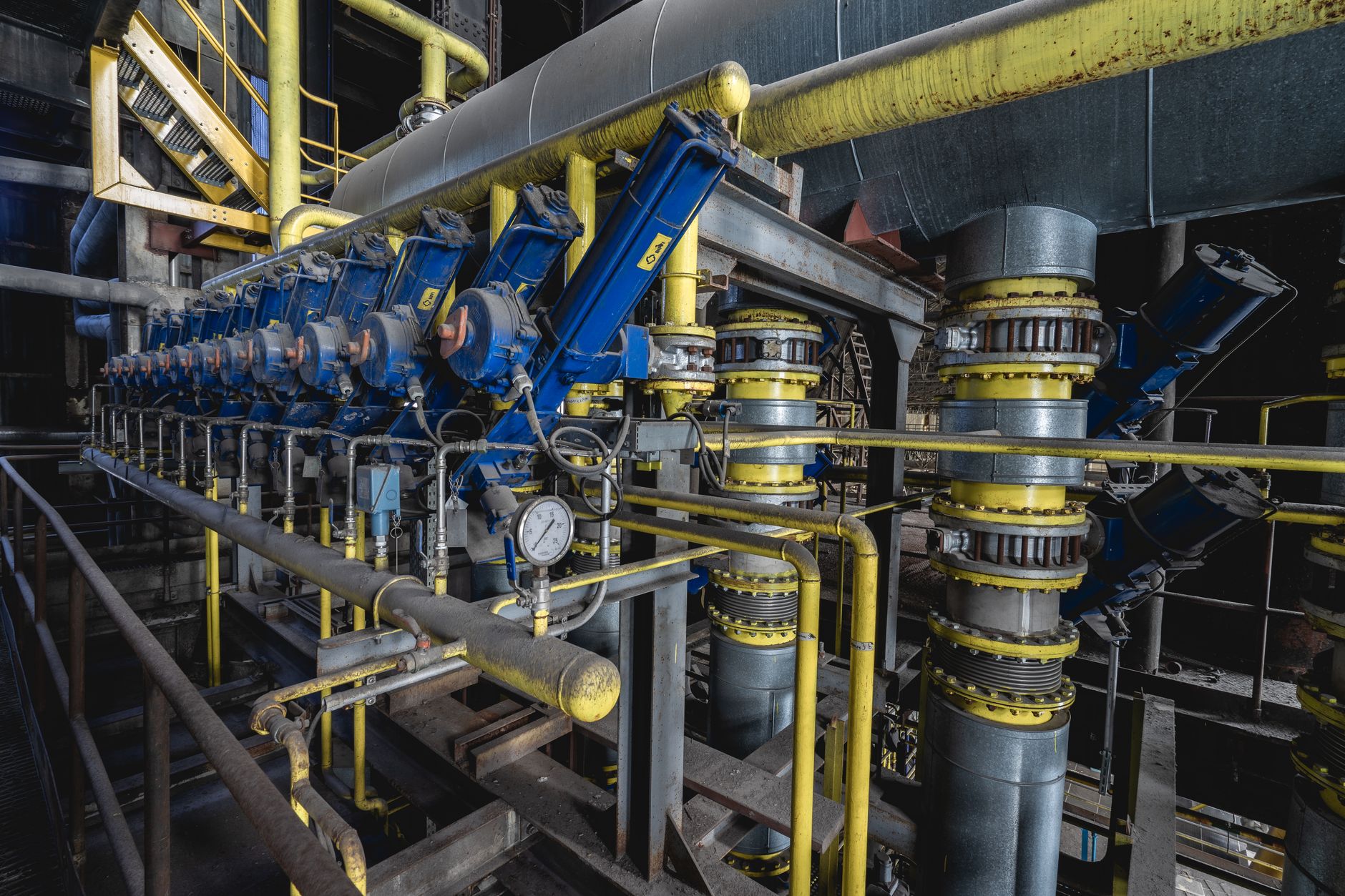 close-up of crude oil pipeline infrastructure in a dry industrial landscape, valves and gauges visible in the foreground