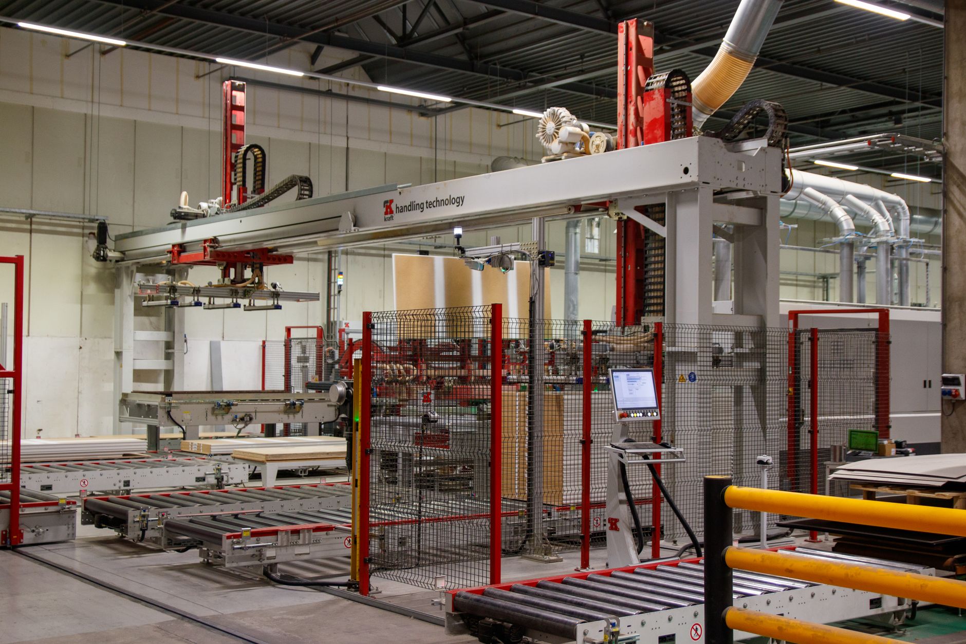 wide-angle view of a large automated manufacturing facility with conveyor systems and robotic arms visible along assembly lines, overhead industrial lighting casting sharp shadows