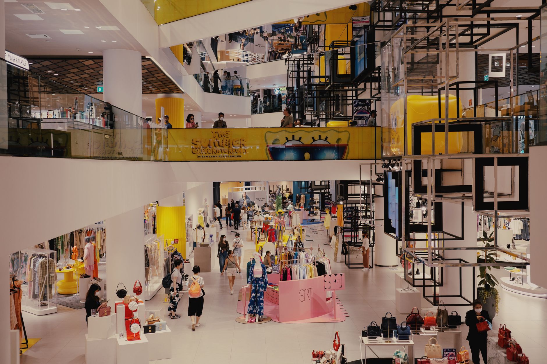 interior of a large, mostly empty shopping mall in a Chinese city, escalators visible and storefronts lit but few shoppers on the floor
