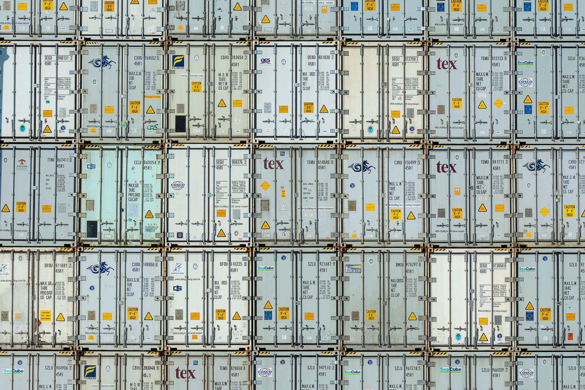 rows of copper cathode sheets stacked inside a large industrial smelting warehouse, lit by harsh overhead lighting