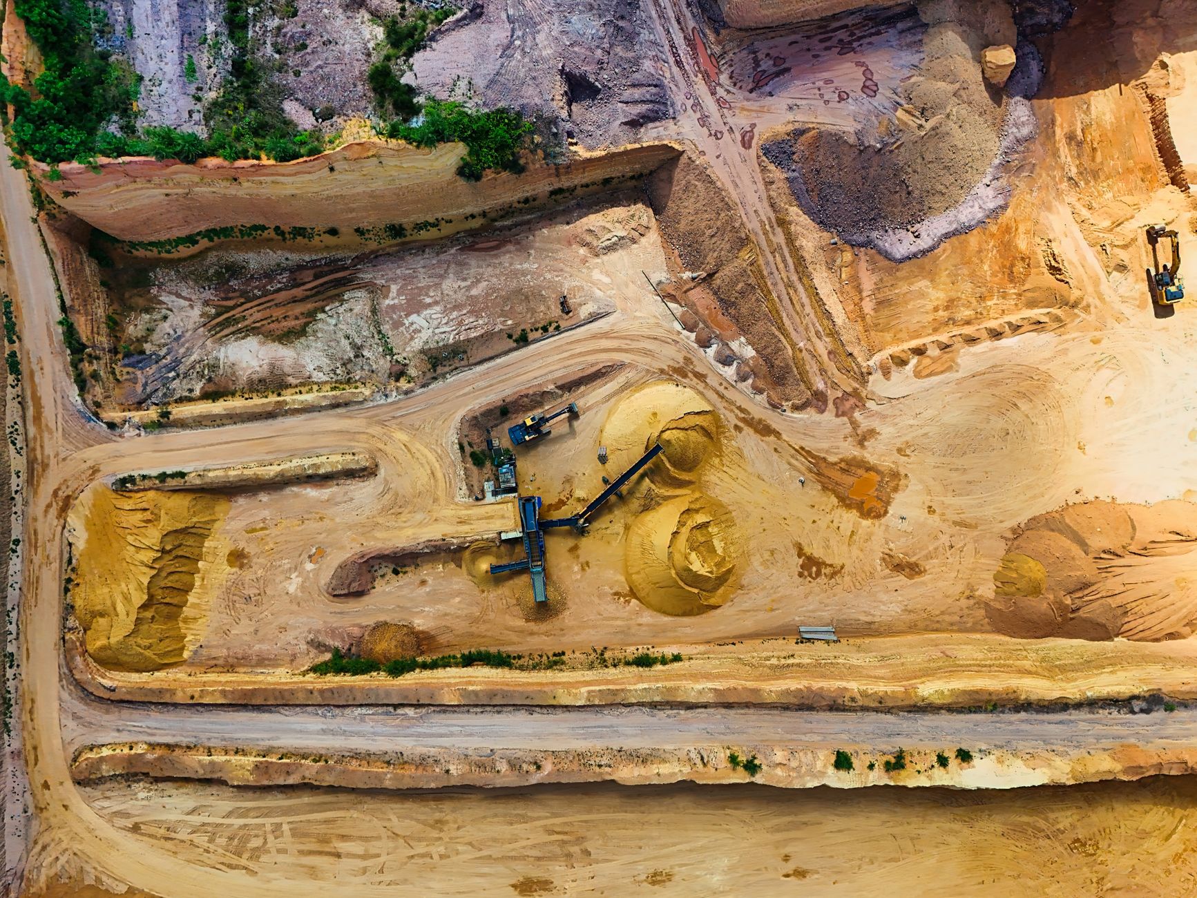 exterior view of an open-pit copper mine in an arid mountainous landscape, with tiered terraced walls and heavy machinery visible below
